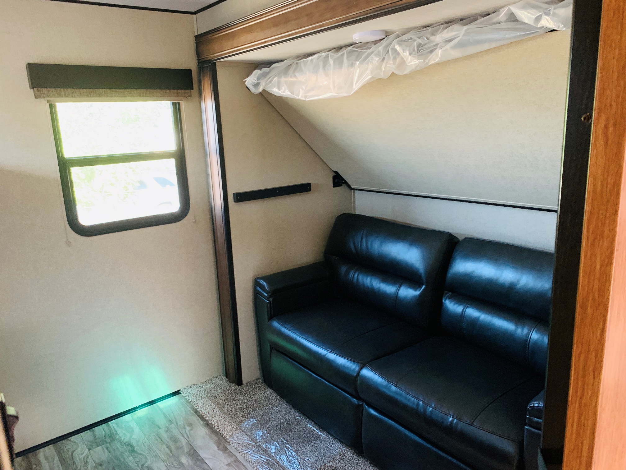 RV rental interior: Cozy living area with a black leather sofa, a fold-up bunk bed, and a bright window.. Grand Design Reflection 2019