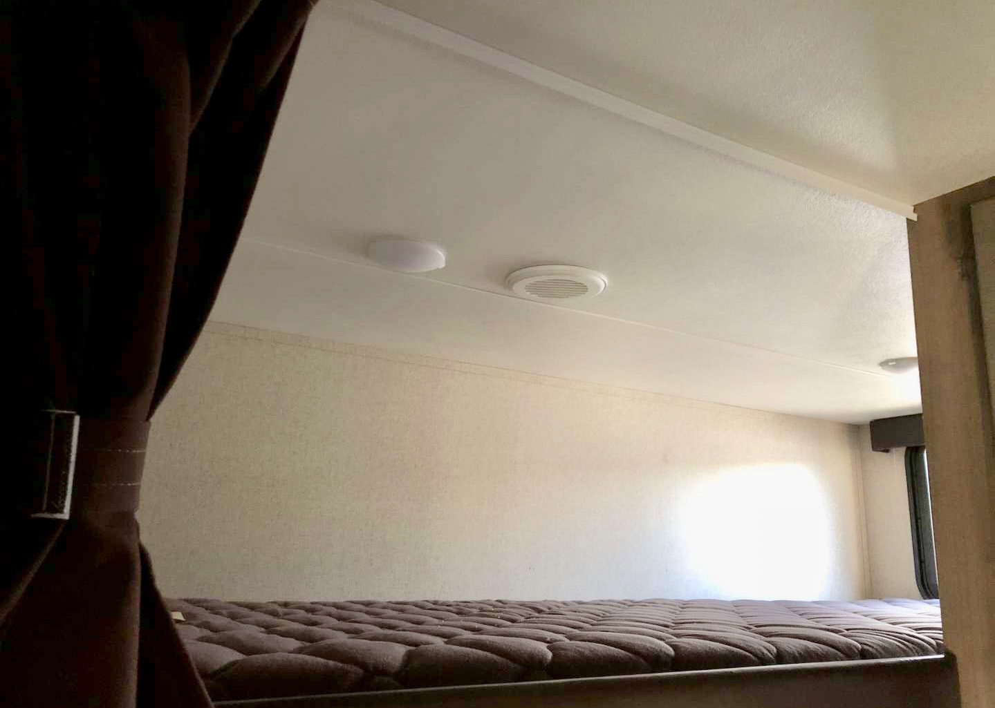 Compact RV rental bunk bed area: soft mattress, overhead light, and AC vent provide comfort for travelers.. Dutchmen Voltage 2019