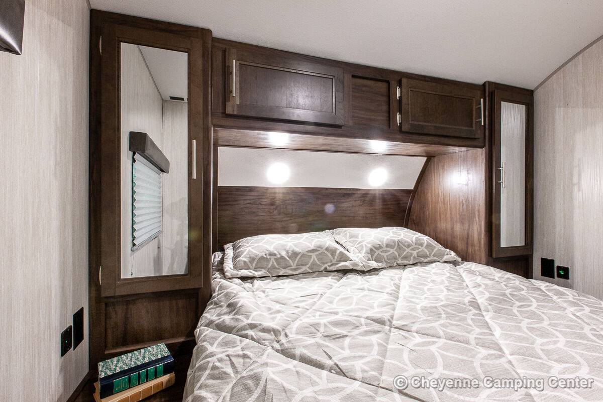 Cozy RV rental bedroom features a comfy bed, overhead storage, and mirrored cabinets. Perfect for travel!. Forest River Cherokee Grey Wolf 2020