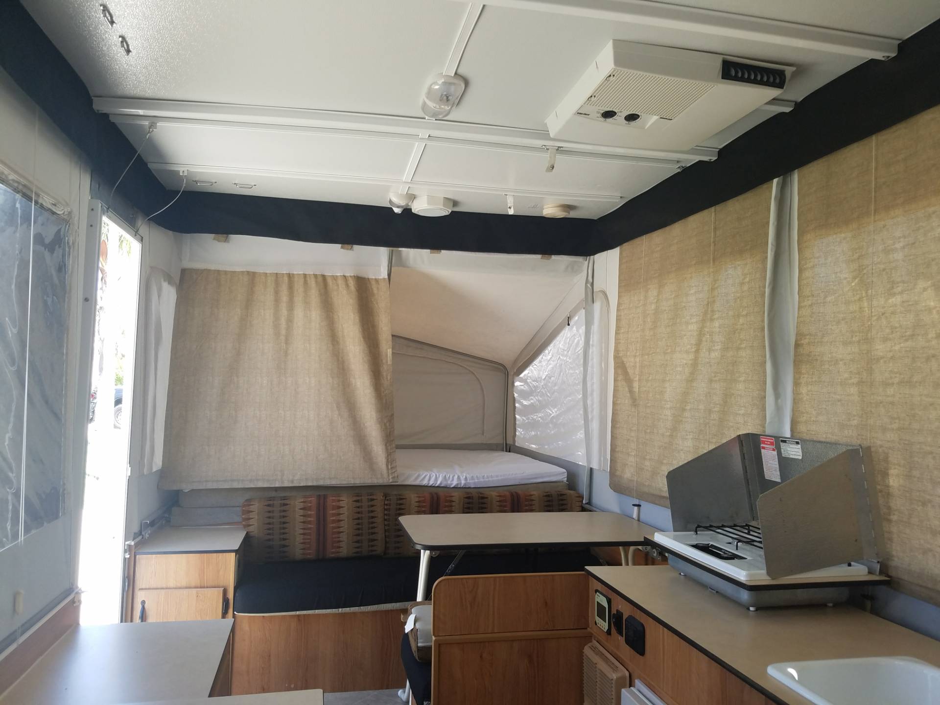 RV rental pop-up camper interior: features dinette, kitchen with stove, and cozy bed for travel.. Jayco Baja 2006