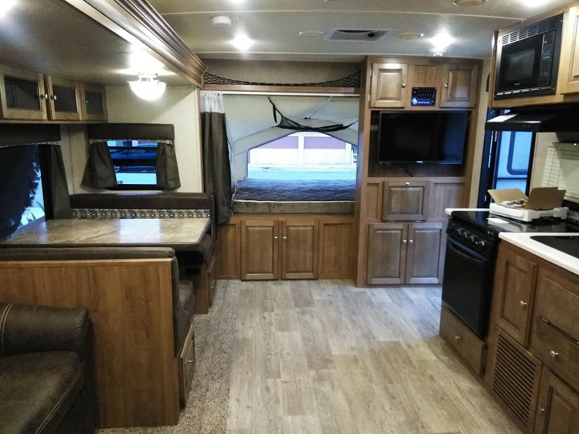 Inside an RV rental: dining area, sofa, kitchen, and a comfortable pop-out bed, offering ample living space for travelers.. Forest River Rockwood Roo SS 2018
