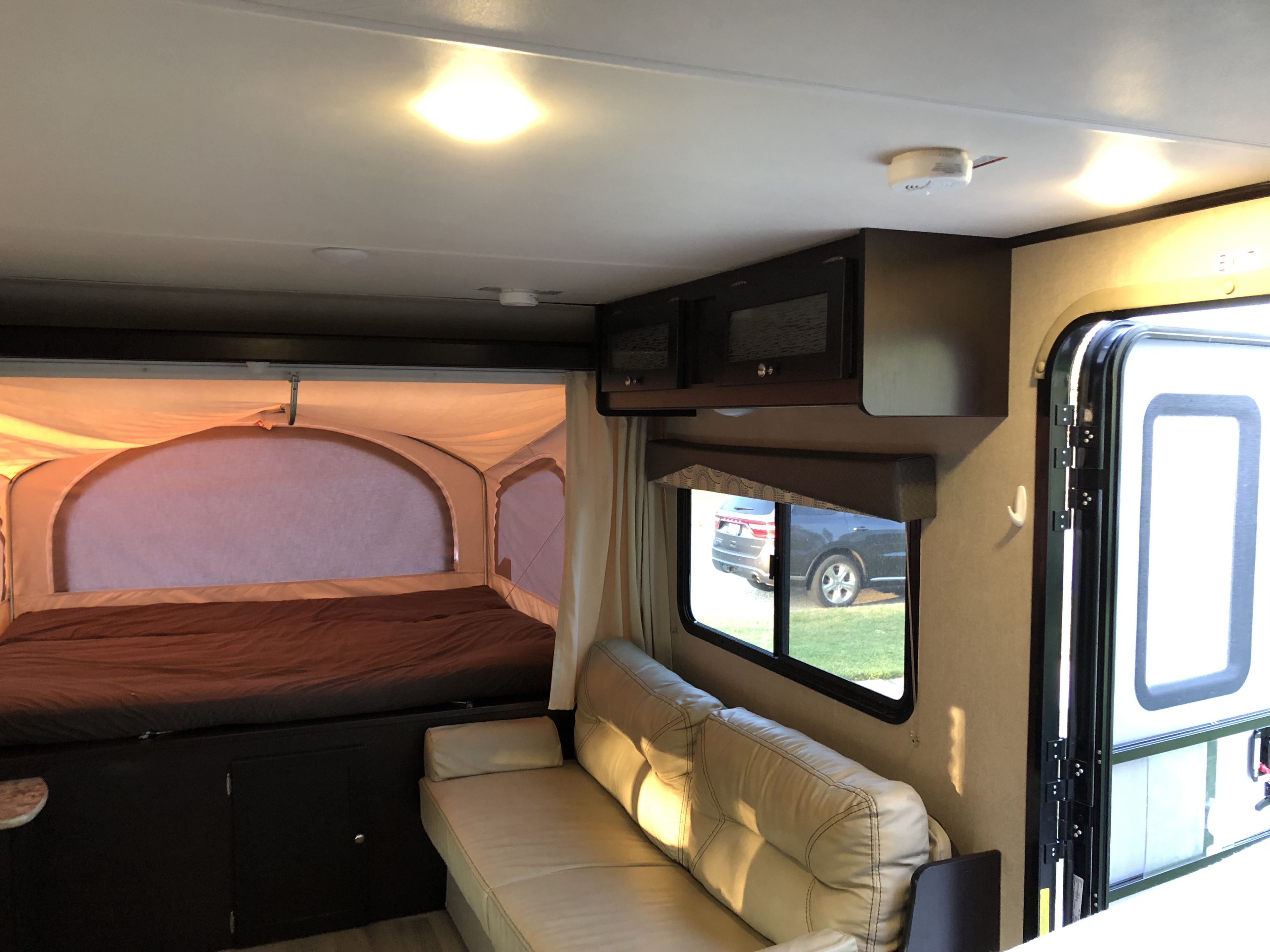 RV rental interior showing a comfortable bed in a pop-out, sofa, and cabinets.. Dutchmen Kodiak 2016