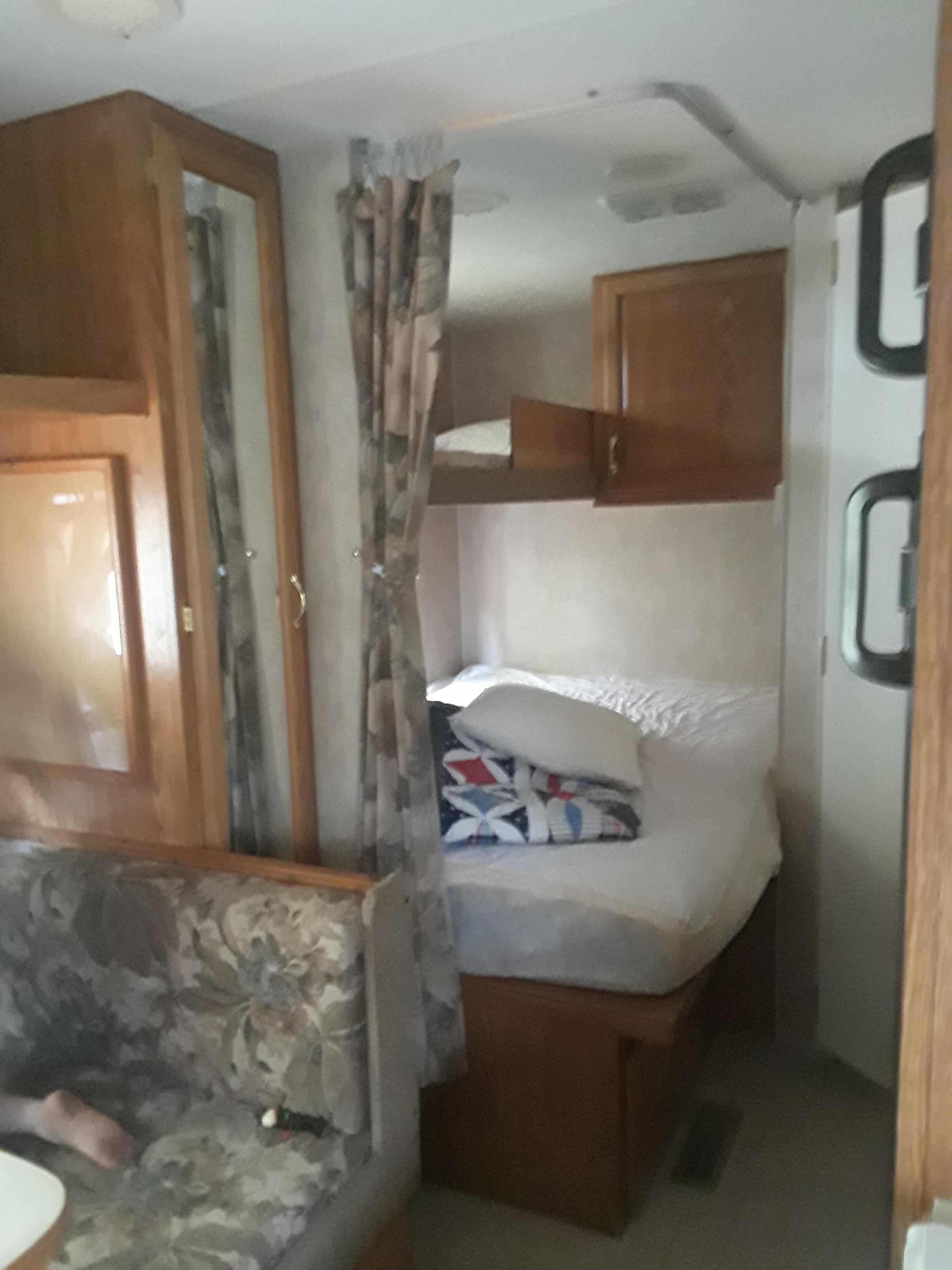 Compact RV rental interior: living space with patterned dinette, cozy bunk beds, and wood cabinetry. Ready for your trip!. Fleetwood Pioneer 2004