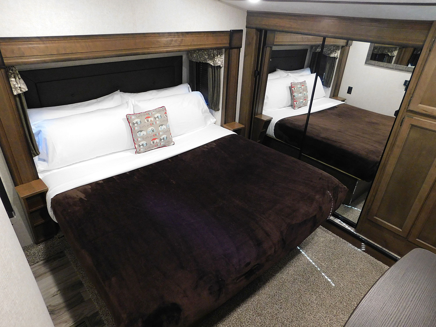RV rental bedroom: a comfy bed with white linens, brown blanket, and large mirrored closet doors.. KEYSTONE 369BHS 2019