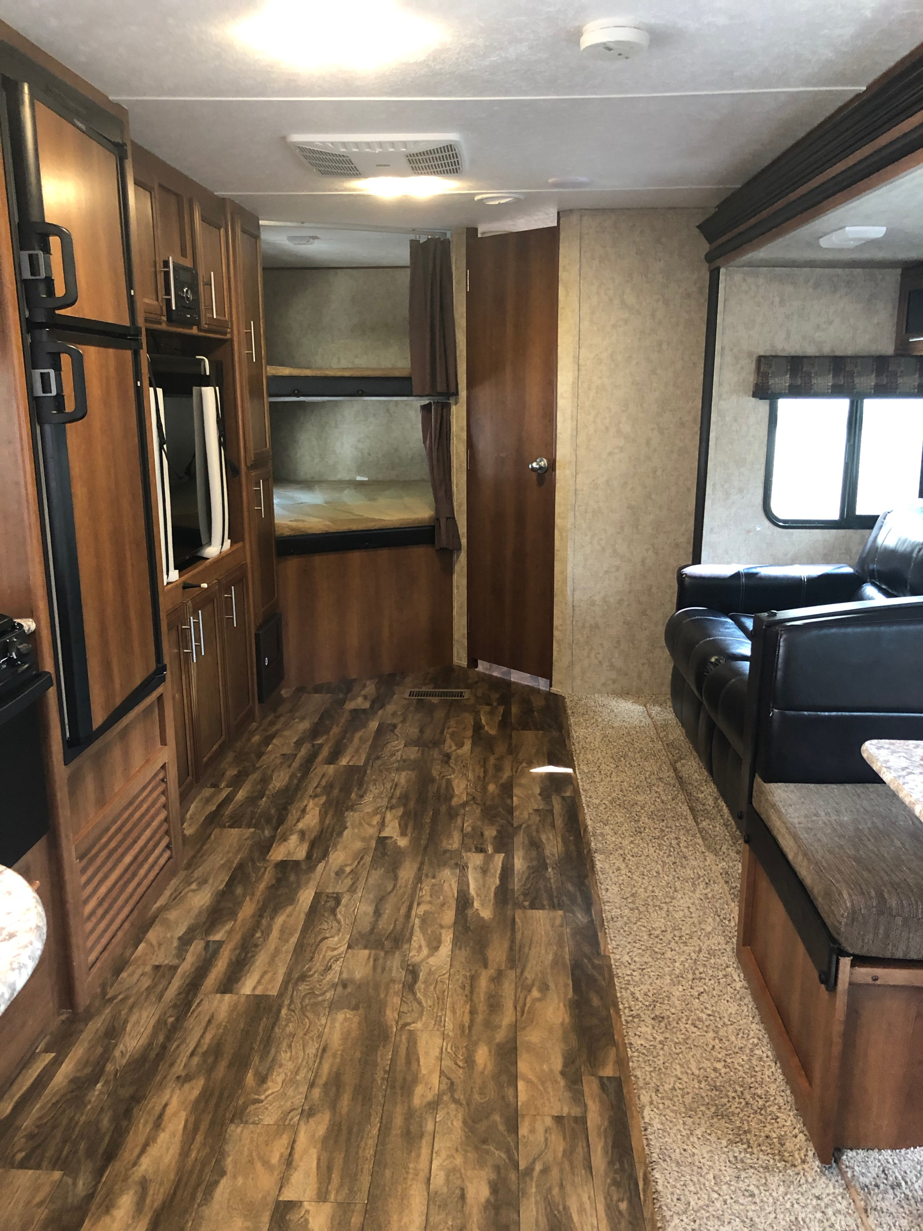 An RV rental's inviting interior showing kitchen, bunk beds, and a comfy sofa. Ideal for travel trailer exploration.. Prime Time Avenger 2018