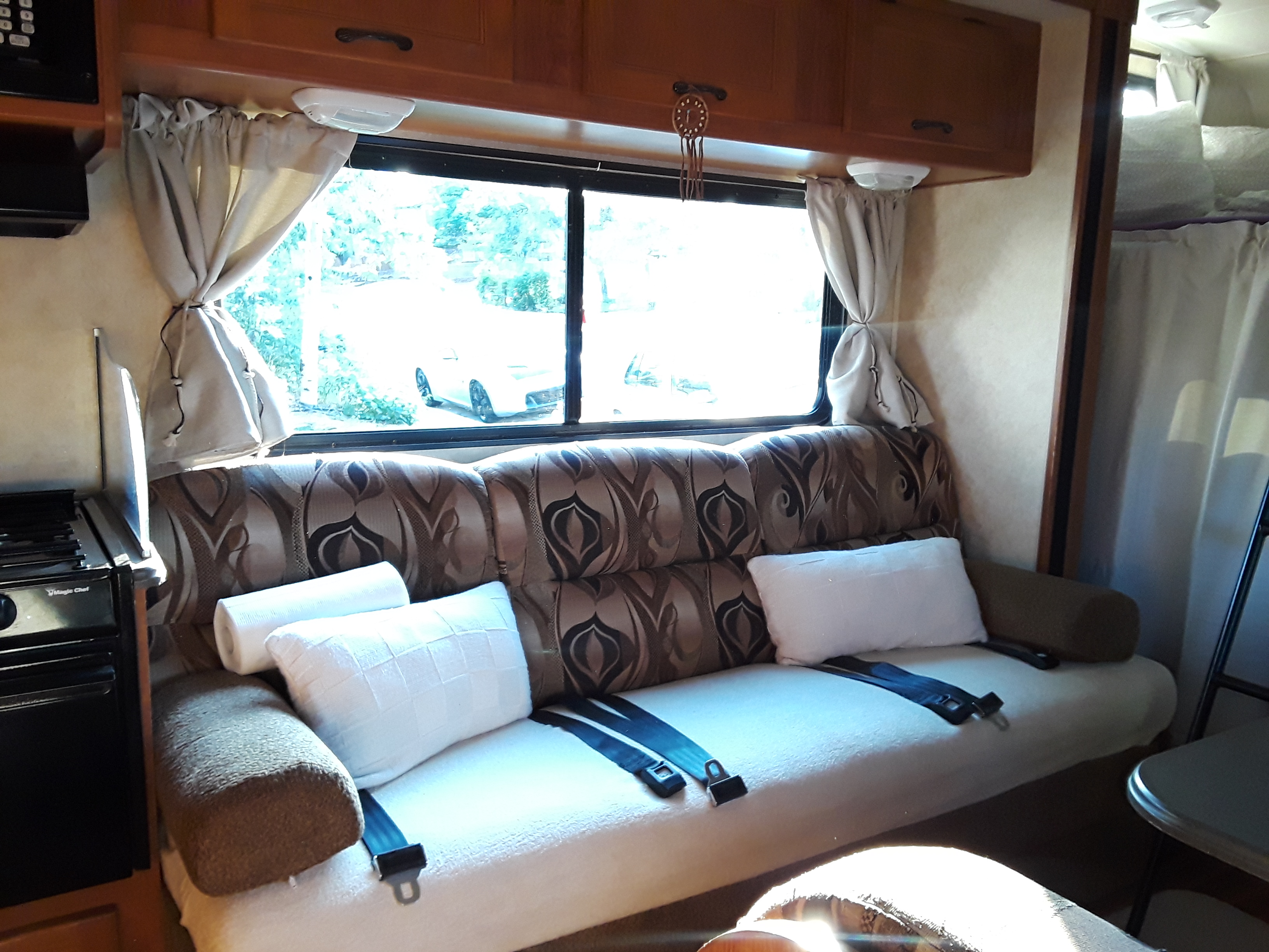 Relax in your RV rental's comfy dinette with a scenic window view, curtains, seatbelts, and small kitchen.. Coachmen Freelander 2011