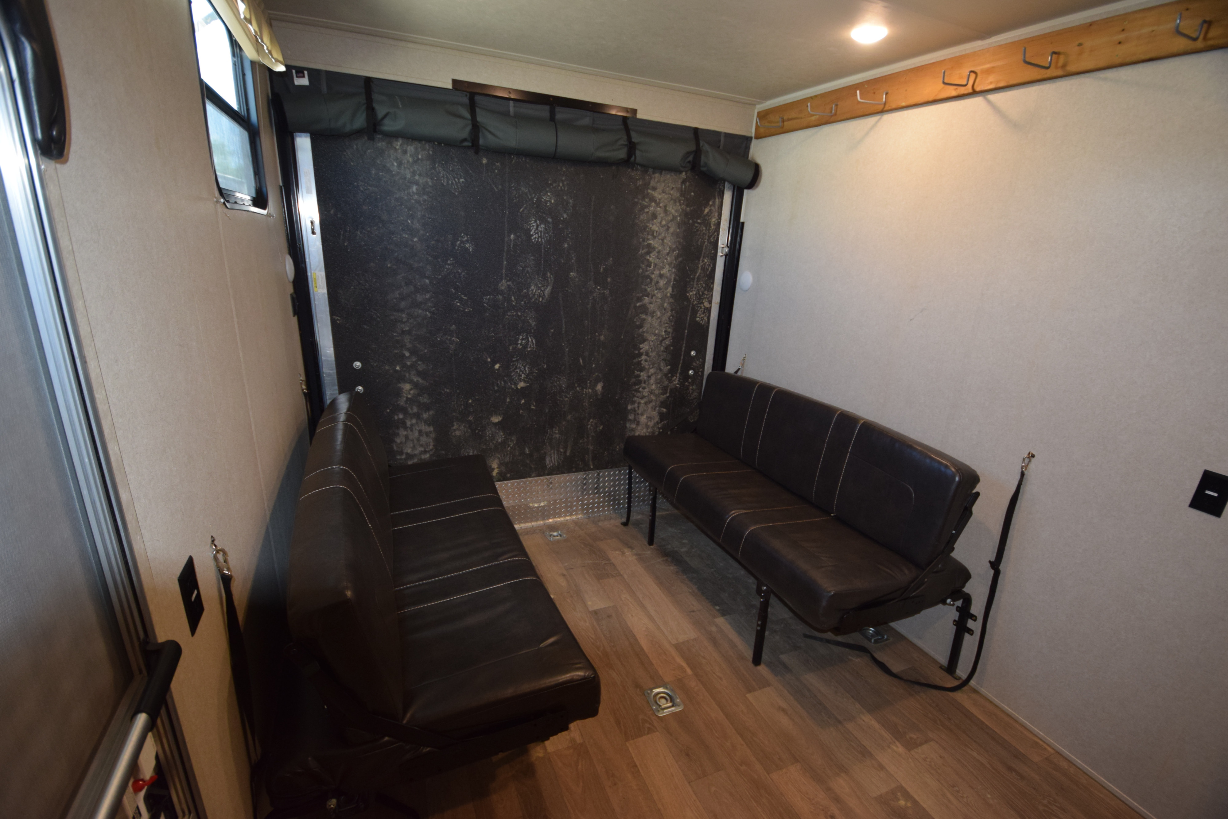 RV rental toy hauler garage with black cargo wall, two dark benches, durable flooring, and wall hooks.. Palomino Puma XLE 2019