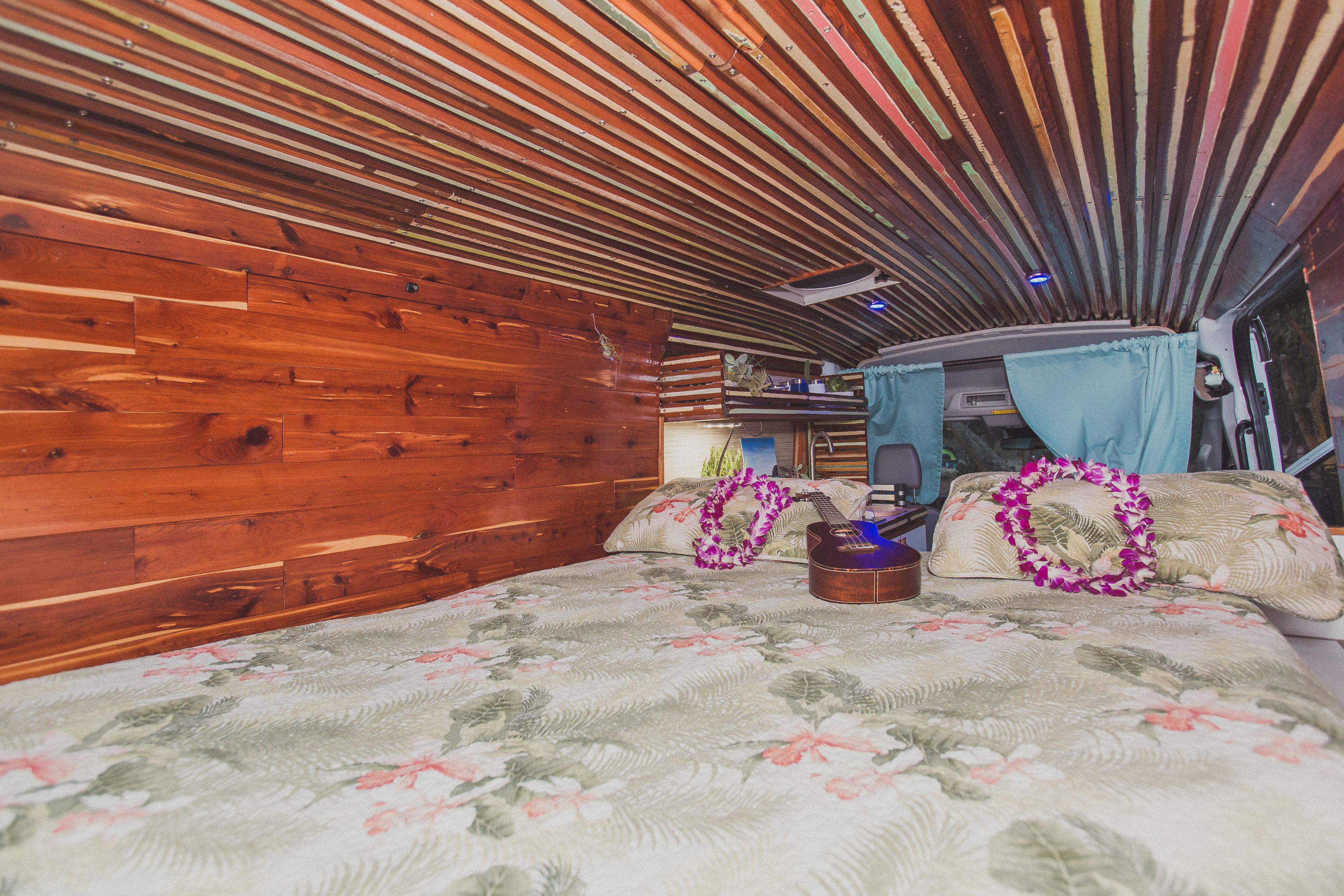 Step into this unique RV rental: a cozy bed with ukulele & leis, surrounded by custom wood walls and ceiling.. Ford Transit 2016