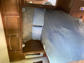 This cozy RV rental bedroom features a queen bed, built-in storage, and reading lights, perfect for your travel accommodation.. Coachmen Freedom Express - Liberty Edition 2017