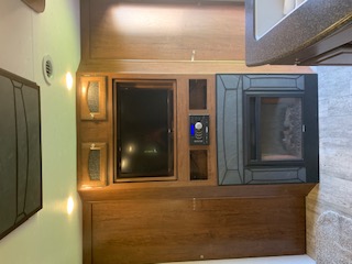 Cozy RV rental living space featuring a built-in TV, stereo, and electric fireplace within warm wood cabinetry.. Coachmen Freedom Express - Liberty Edition 2017