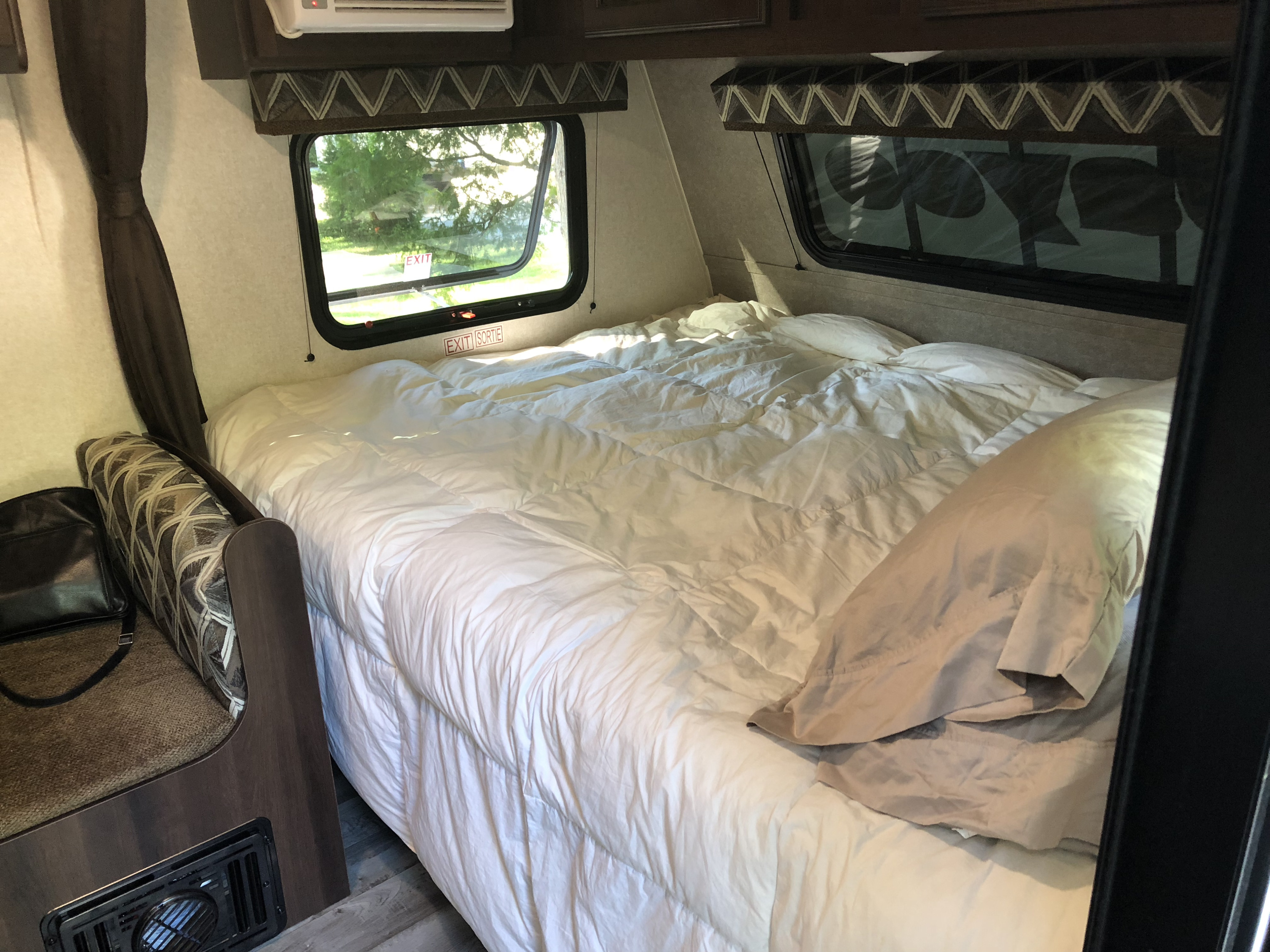 Bright and spacious **rv rental** bedroom featuring a large, inviting bed with white bedding, two windows, and cozy seating.. Jayco Jay Flight 2018