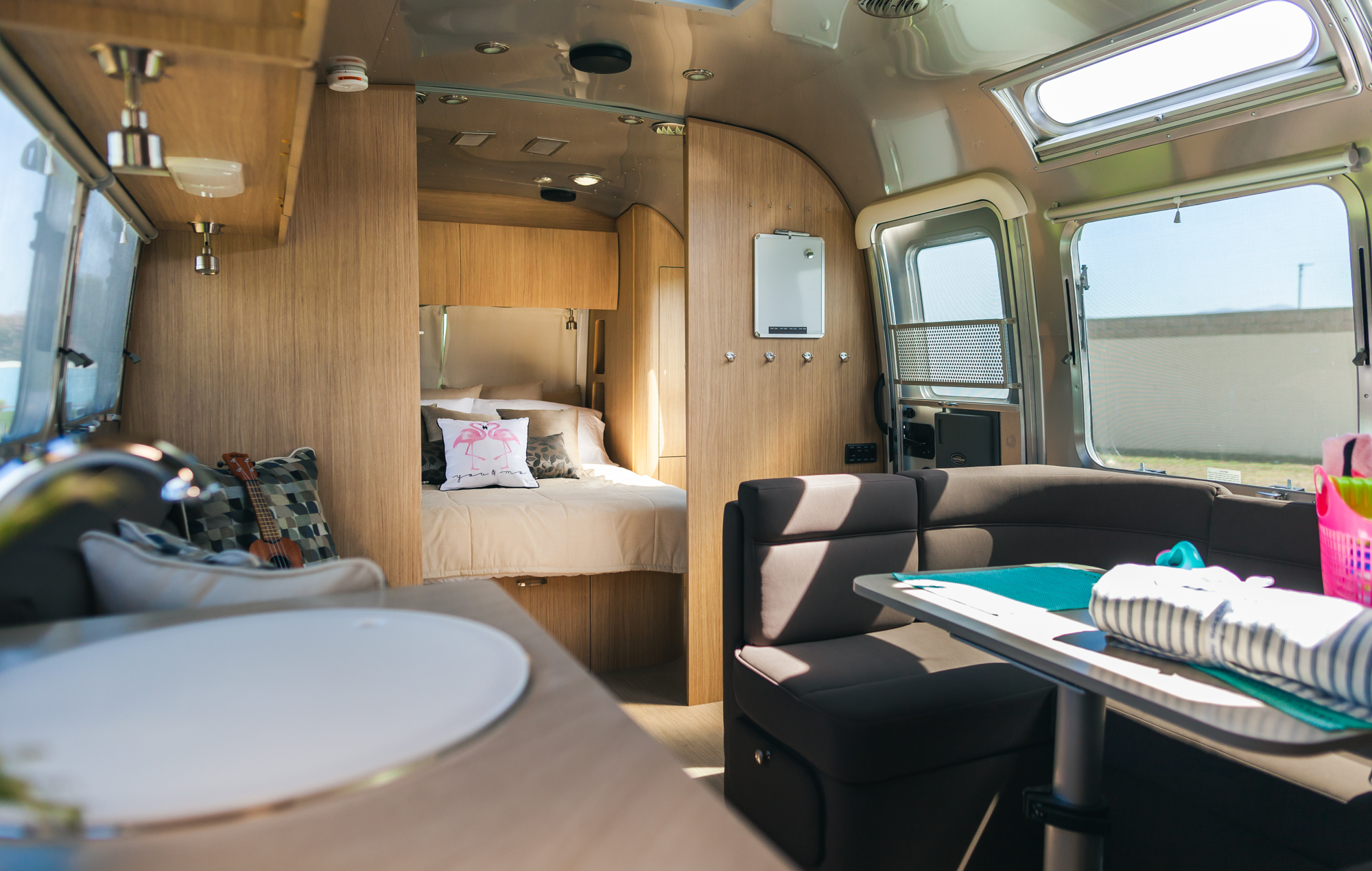 Step into this modern RV rental's interior: a cozy bedroom with a bed, plus a bright living and dining area.. Airstream Flying Cloud 2020