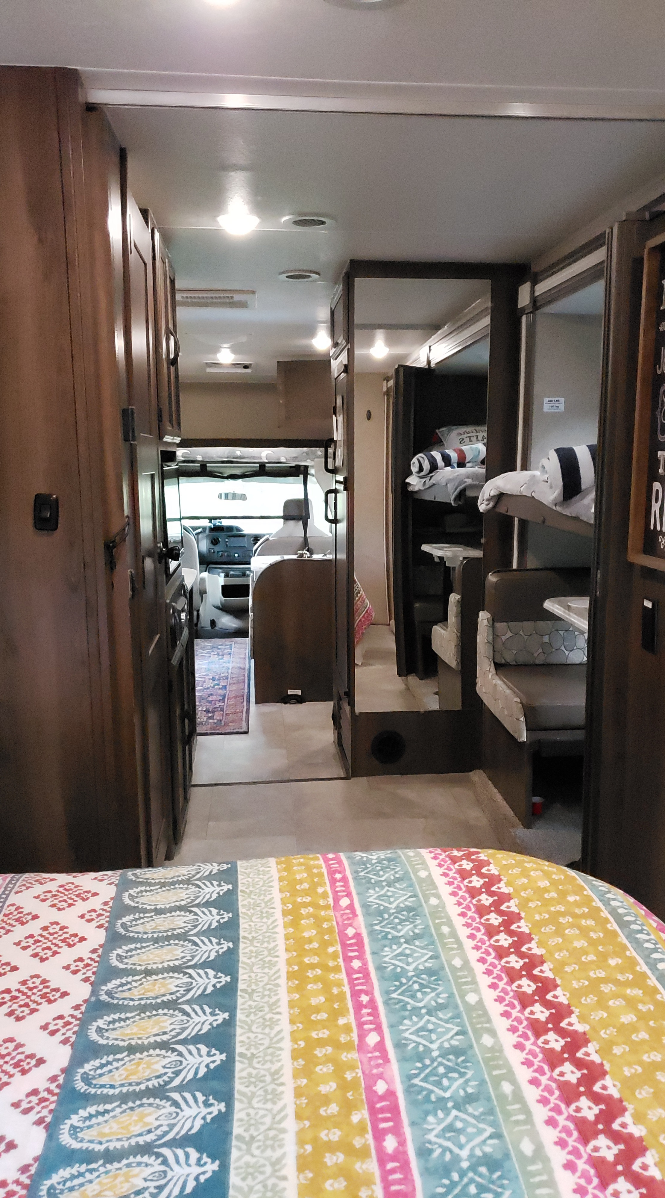 Spacious RV rental interior featuring a hallway, bunk beds, dinette, and cockpit view, providing comfort for travel.. Coachmen Freelander BH31 2019
