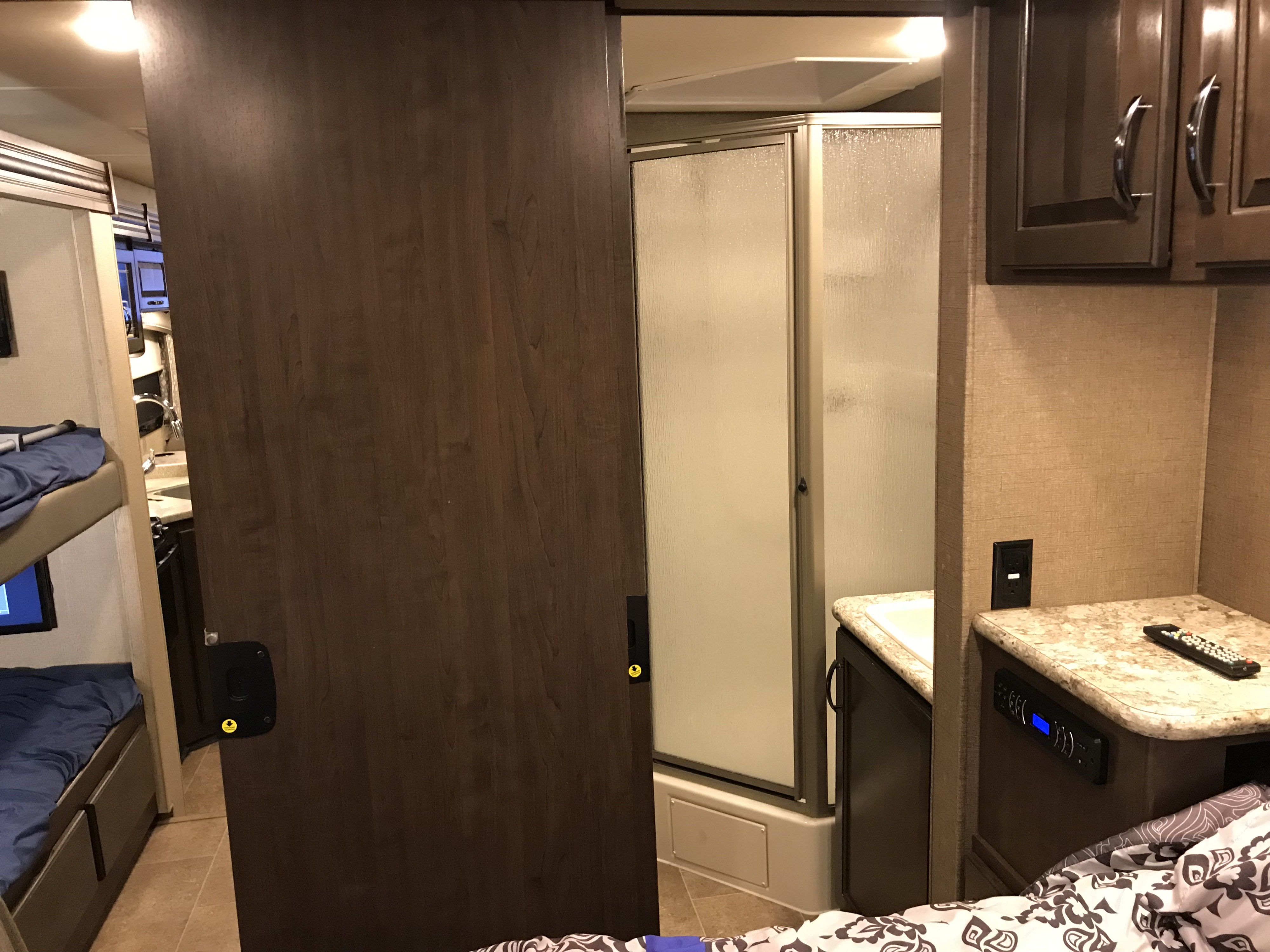 Compact bathroom with shower, sink vanity, and adjacent bunk beds visible in this RV rental interior.. Thor Chateau 2020