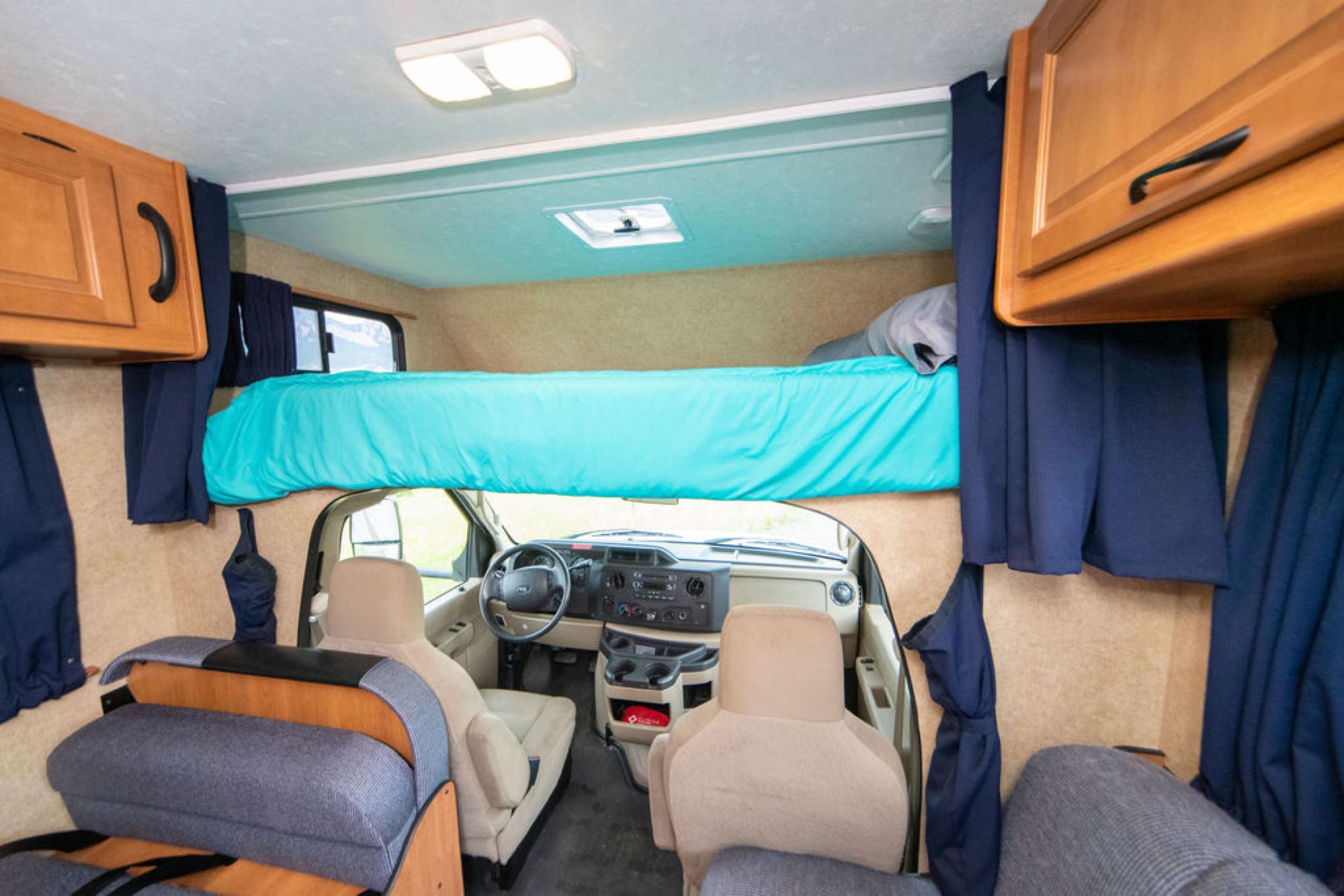 RV rental interior: an over-cab bunk bed, driver's cockpit, and overhead storage cabinets. Ready for your next adventure.. Other Other 2015