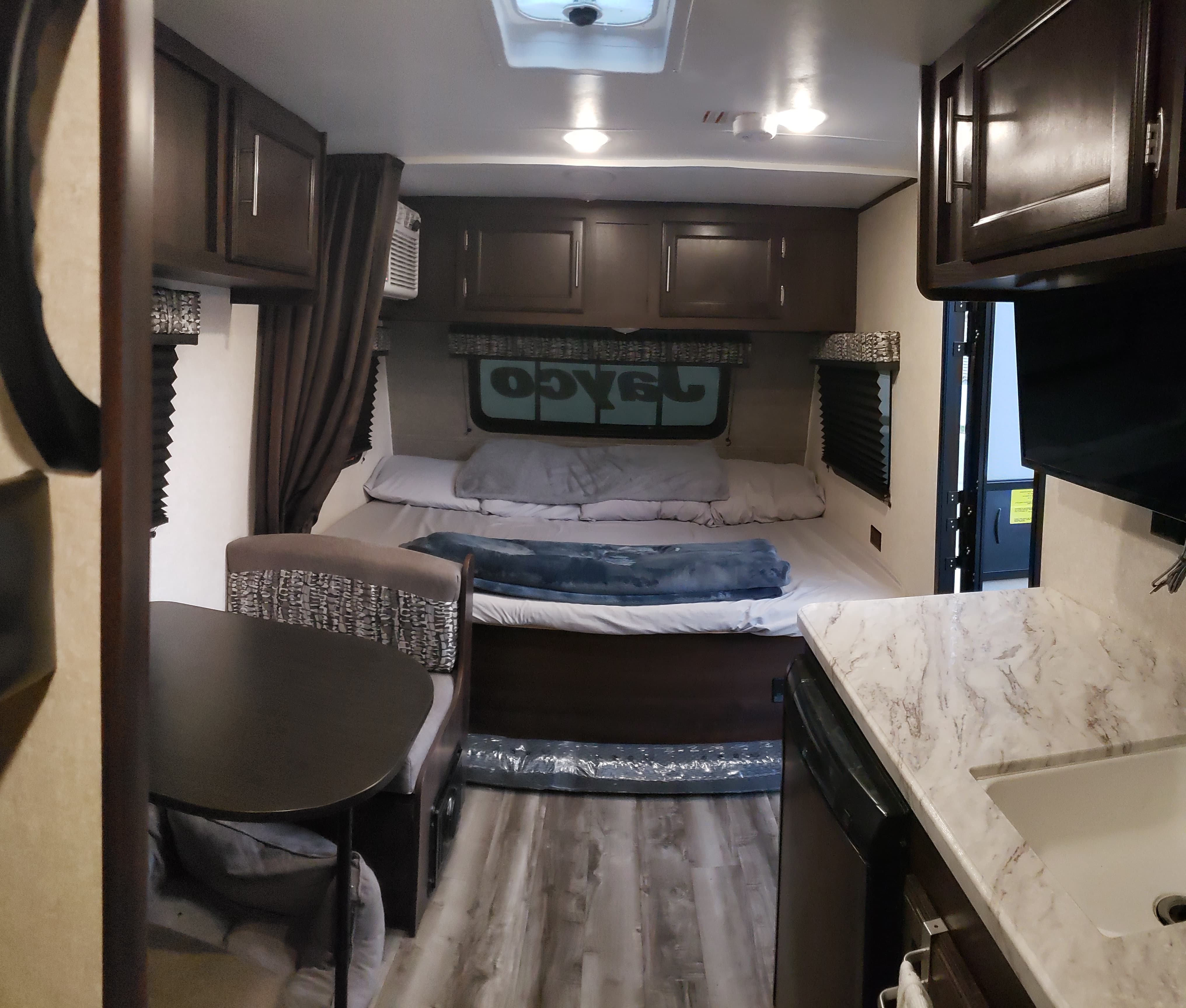 Inside an RV rental: view of a bed, dinette, kitchen counter with sink, and overhead cabinets.. Jayco Jay Flight SLX Baja Edition 2020