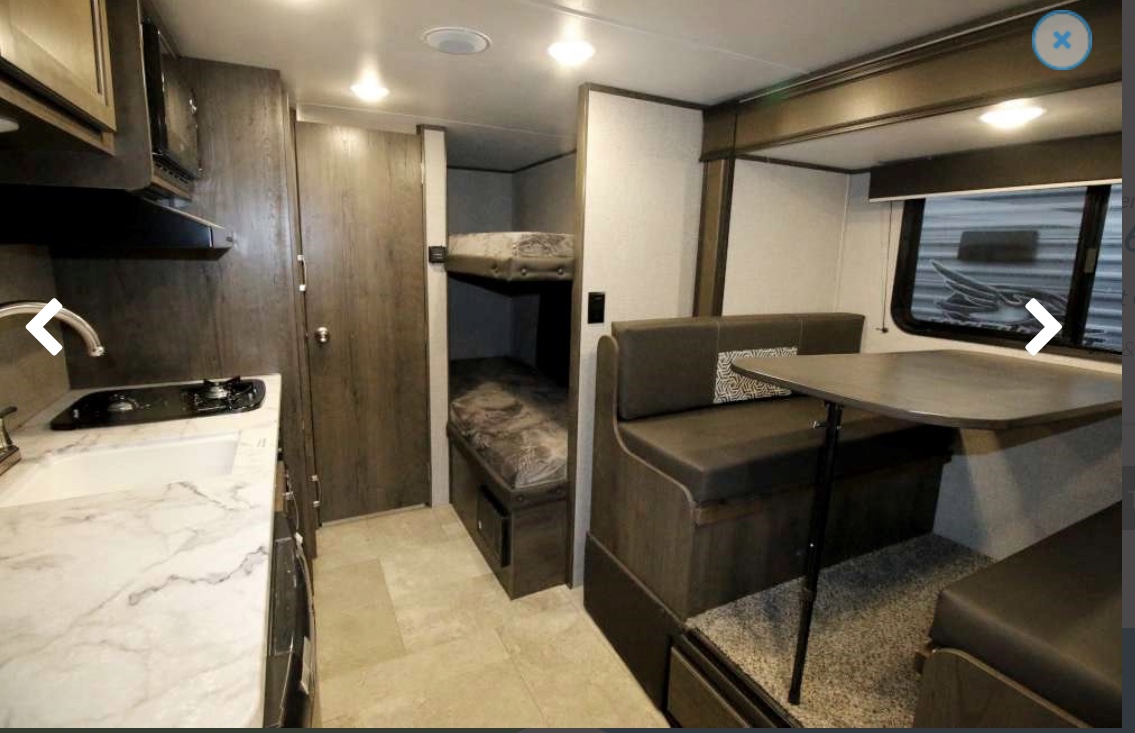 RV rental interior featuring a compact kitchen, bunk beds, and a cozy dinette. Ideal for comfortable travel.. Jayco Baja 2020