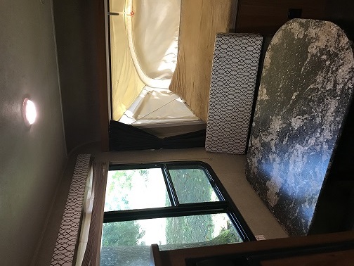 RV rental interior: Pop-up tent bed, patterned cushion, and a dark table by a window, creating a cozy camper space.. Starcraft Launch 2017
