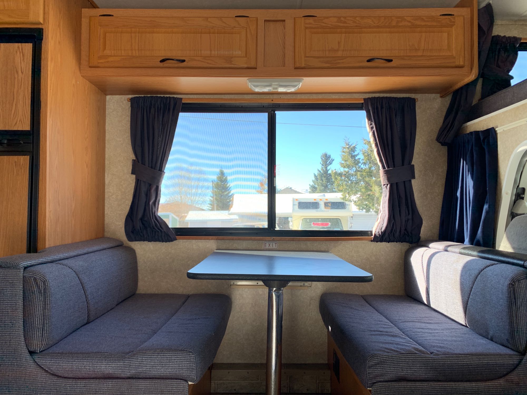 Inside this RV rental: a bright dinette with benches, table, windows, and overhead cabinets. A refrigerator is on the left.. Majestic Leisure Craft Tourer Ii 2007