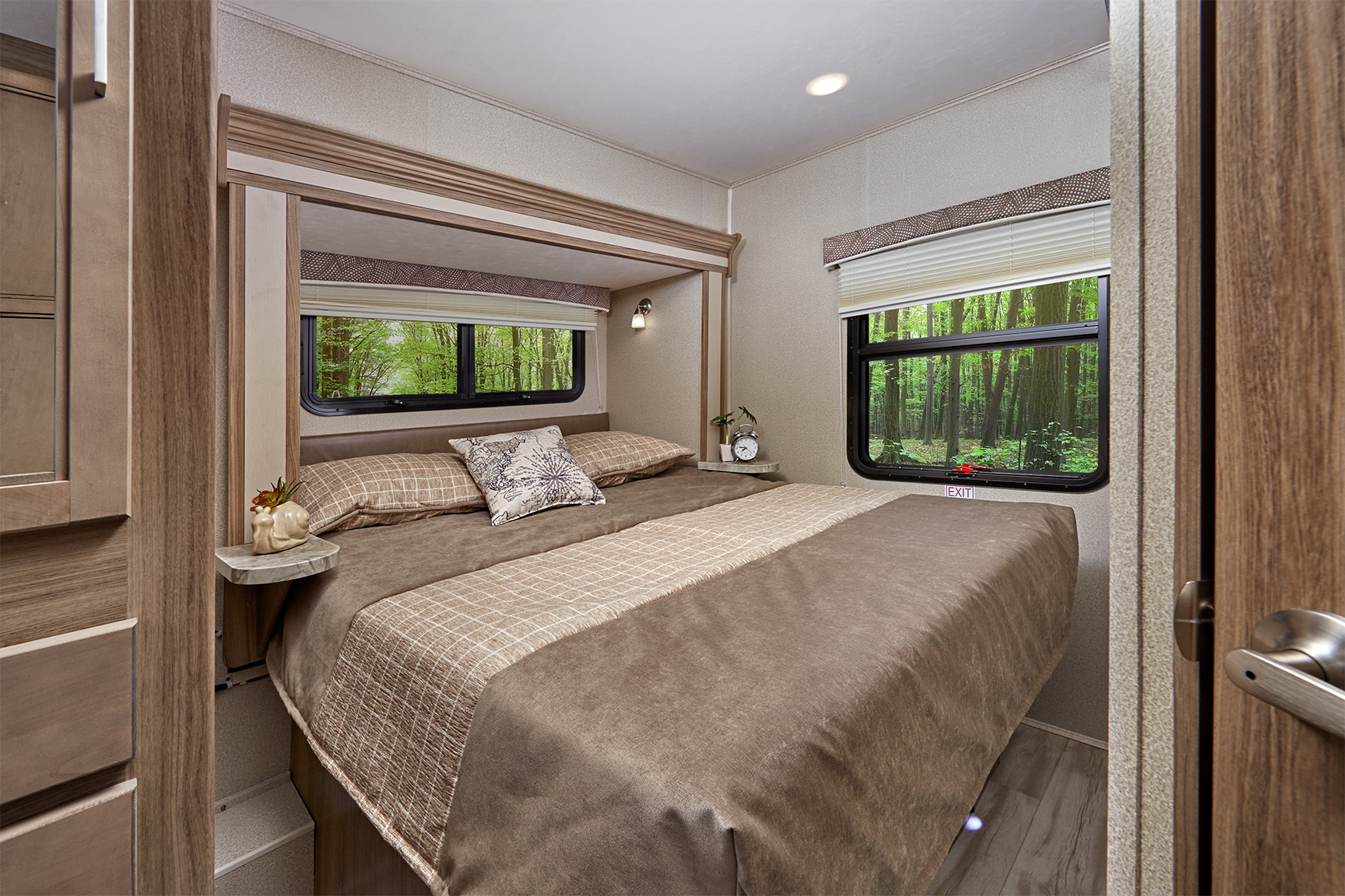 Experience comfort in this RV rental bedroom: cozy bed, built-in storage, and forest views from the windows.. Entegra Coach Odyssey 26D 2021