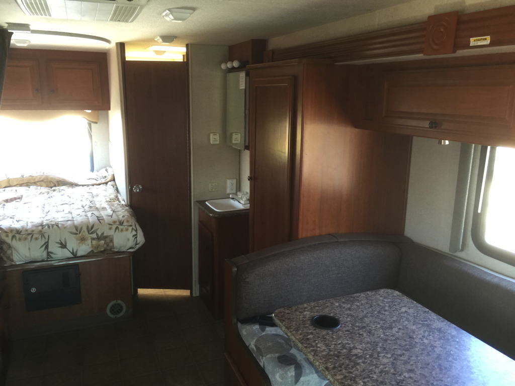 Explore this RV rental's interior: a compact living space featuring a comfy bed, dinette, and sink. Ready for adventure!. Fleetwood Tioga Ranger 25G 2011