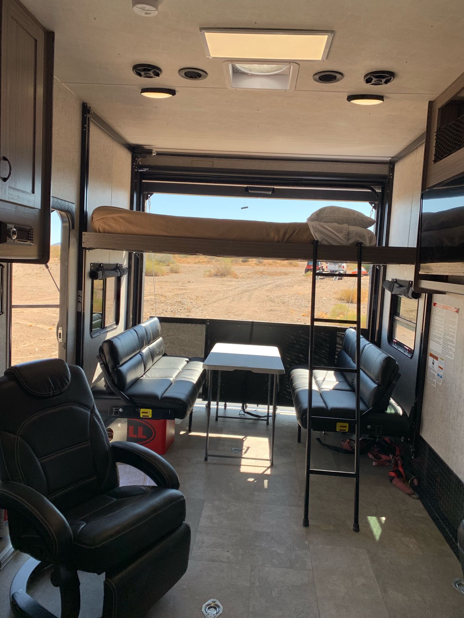 Spacious rv rental interior with a bunk bed, seating, and an open ramp revealing a desert view. Ideal for adventures.. Coachmen Adrenaline 2020
