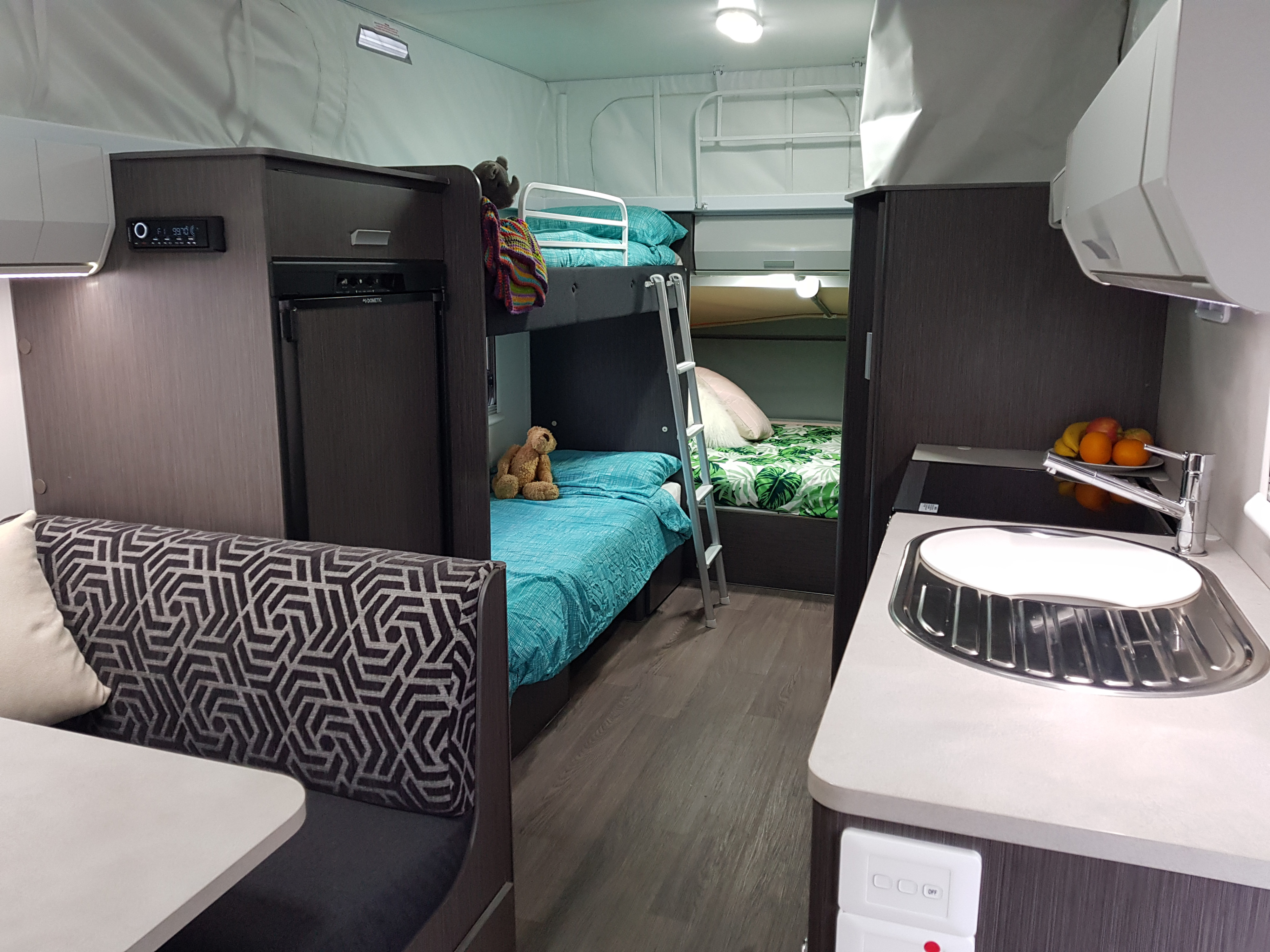 Inside a modern RV rental featuring comfortable bunk beds, a cozy dinette, and a compact kitchen area.. Expanda Outback 2018