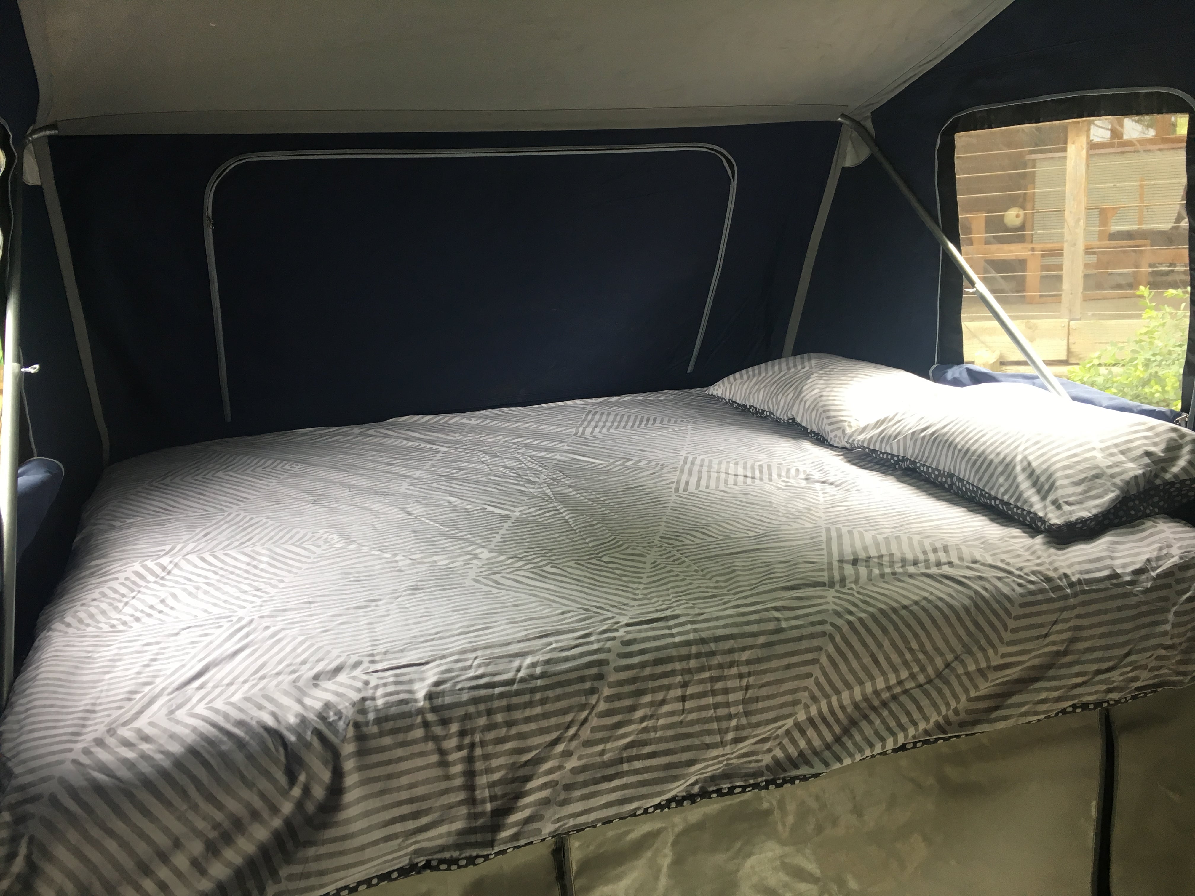 Cozy and spacious bed in an RV rental, featuring a gray patterned comforter. Ideal sleeping area for camping adventures.. Johnno's Off-Road 2015