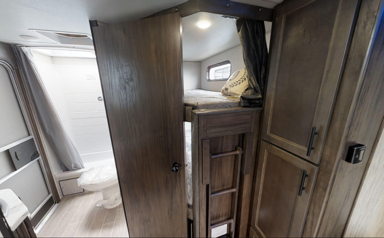 RV rental interior featuring comfortable bunk beds with a ladder, ample storage cabinets, and a compact bathroom.. Forest River Cherokee Grey Wolf 2020