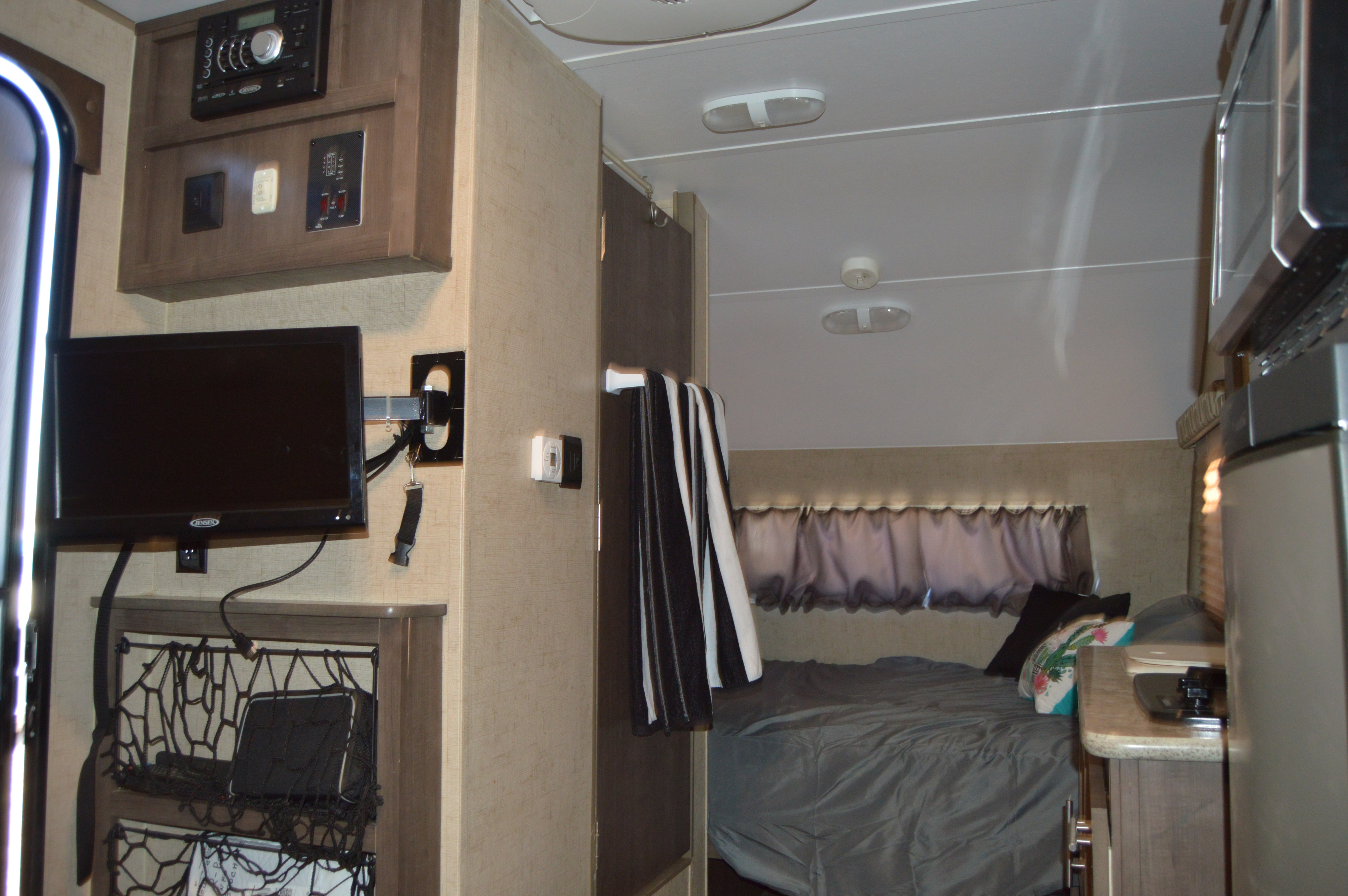 Compact RV rental living space with a cozy bedroom, TV, and kitchen area. Perfect for your next travel trailer adventure.. Forest River Flight SLX 7 2015