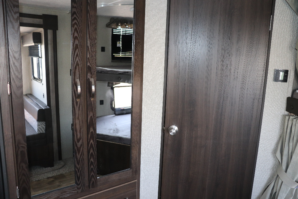 Spacious RV rental interior with dark wood-look doors, featuring bunk beds reflected in a mirror and a dinette.. Keystone Springdale 2020