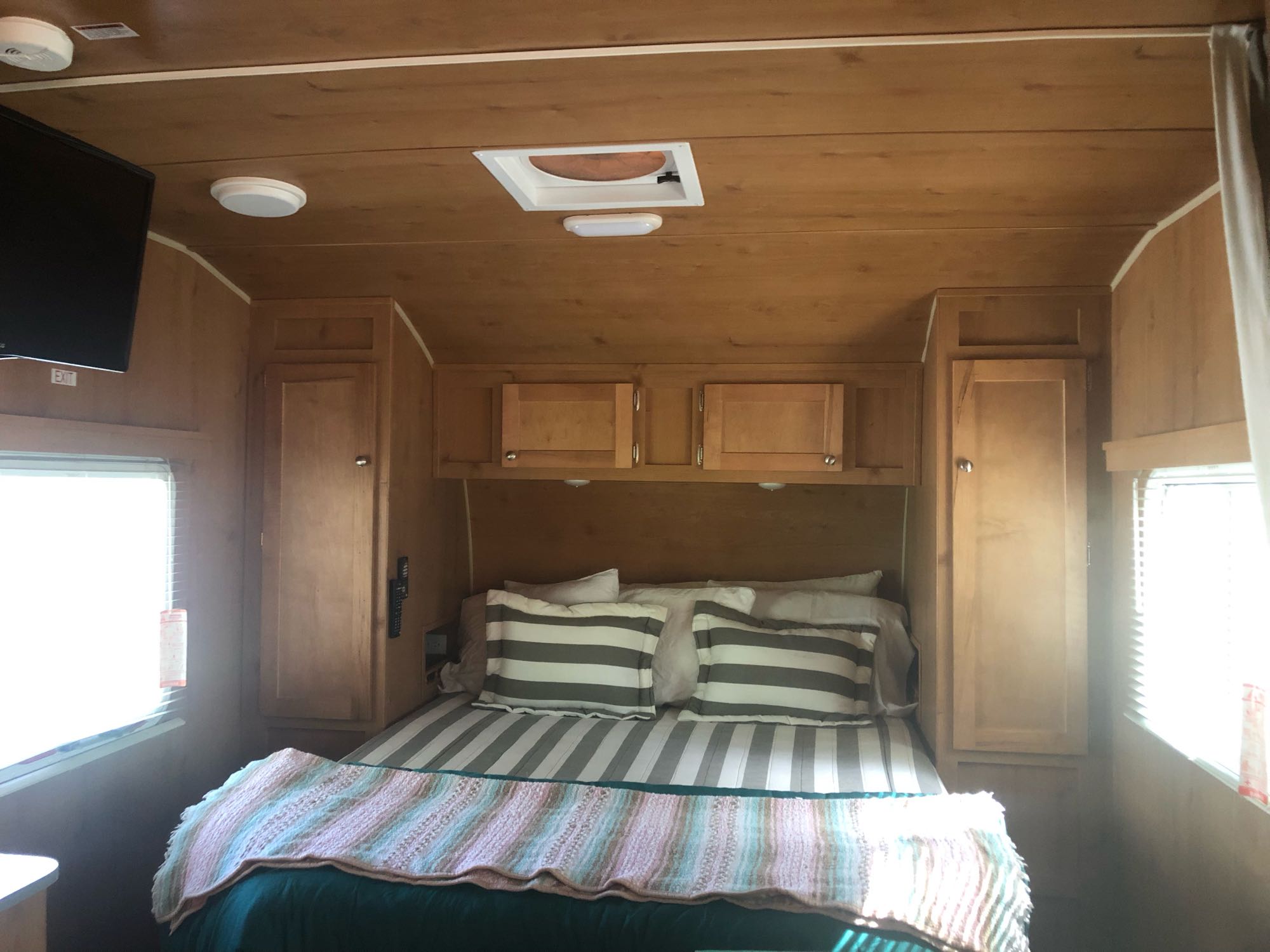 Cozy rv rental bedroom features a comfortable bed, wood walls, ample storage, and TV. Ideal for your mobile adventures.. Riverside Rv 189R Retro 2018