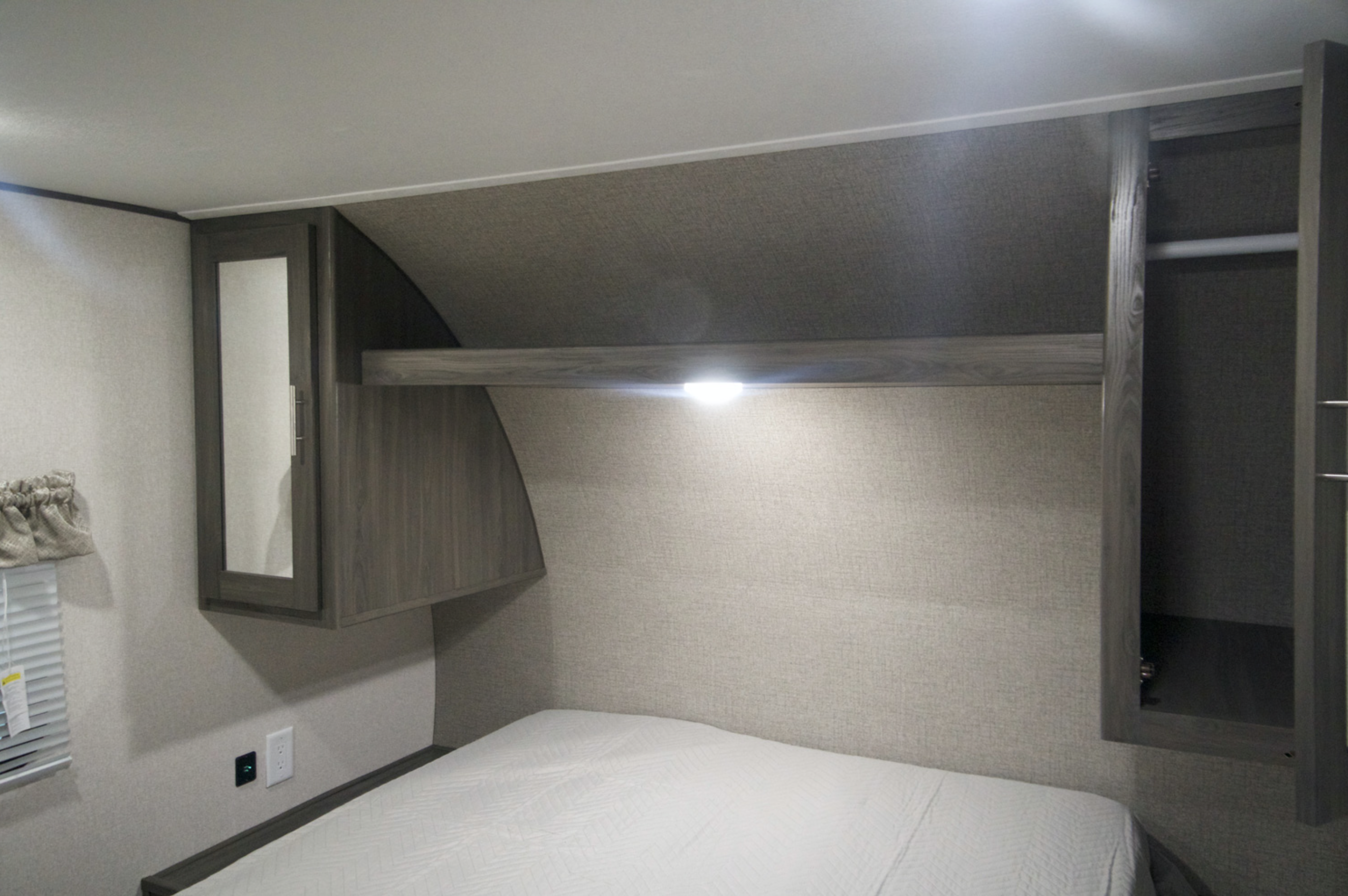 Inside an rv rental, a bedroom with a bed, mirrored cabinet, open closet, reading light, and window for comfort.. Shasta Oasis 2019