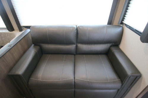 This dark grey two-seater sofa with visible white stitching offers comfort in an RV rental.. Keystone Hideout 2020
