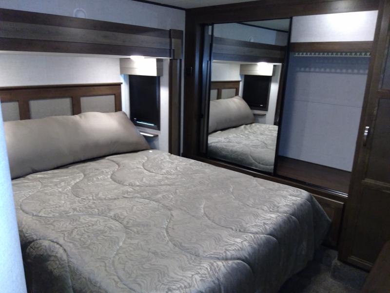 Comfortable RV rental bedroom featuring a cozy bed, mirrored closet, and ambient lighting.. Highland Ridge Mesa Ridge 427BHS 2019