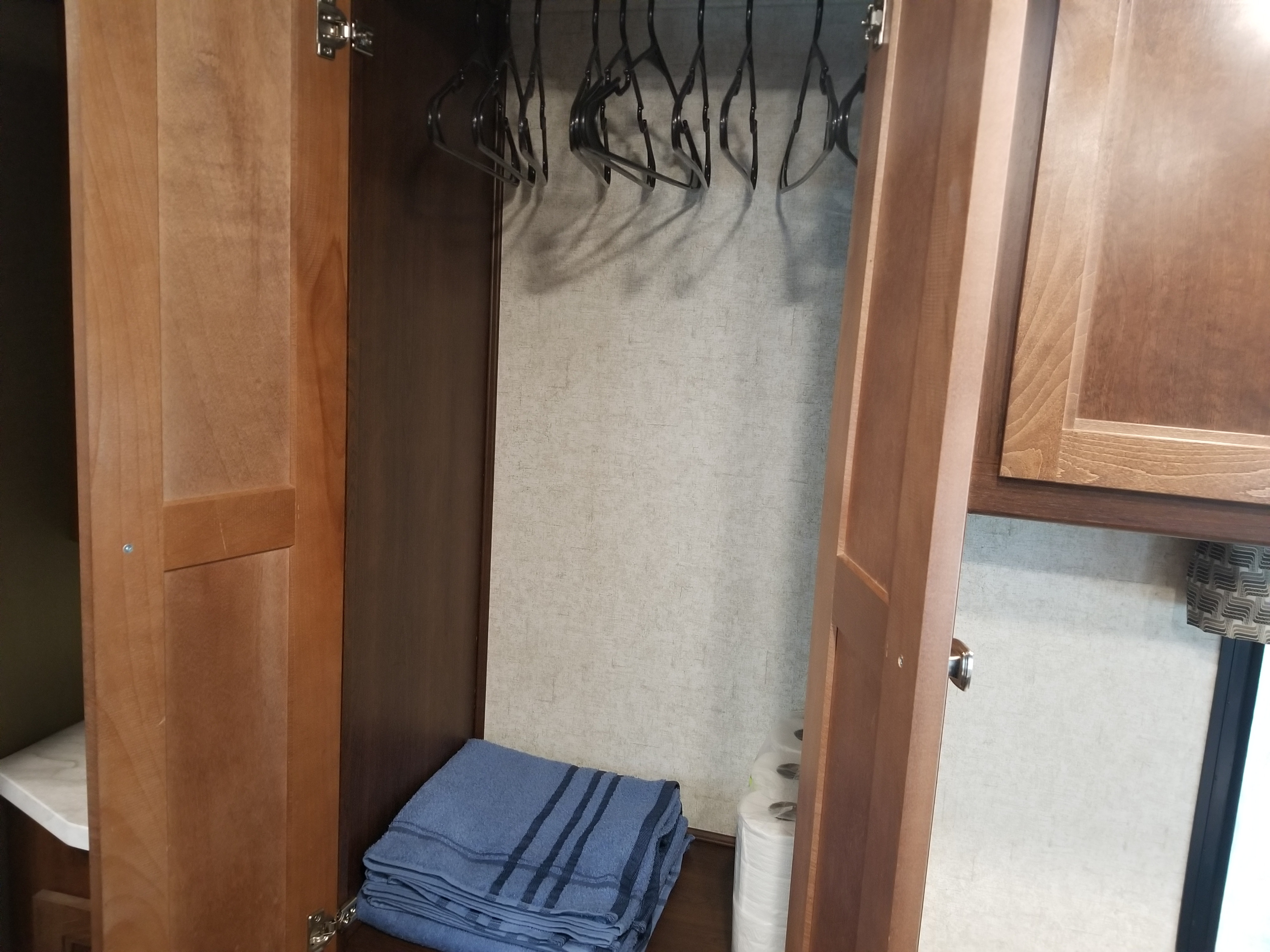 RV rental closet with hangers, stacked blue towels, and paper rolls, ready for your next adventure.. Other Other 2020