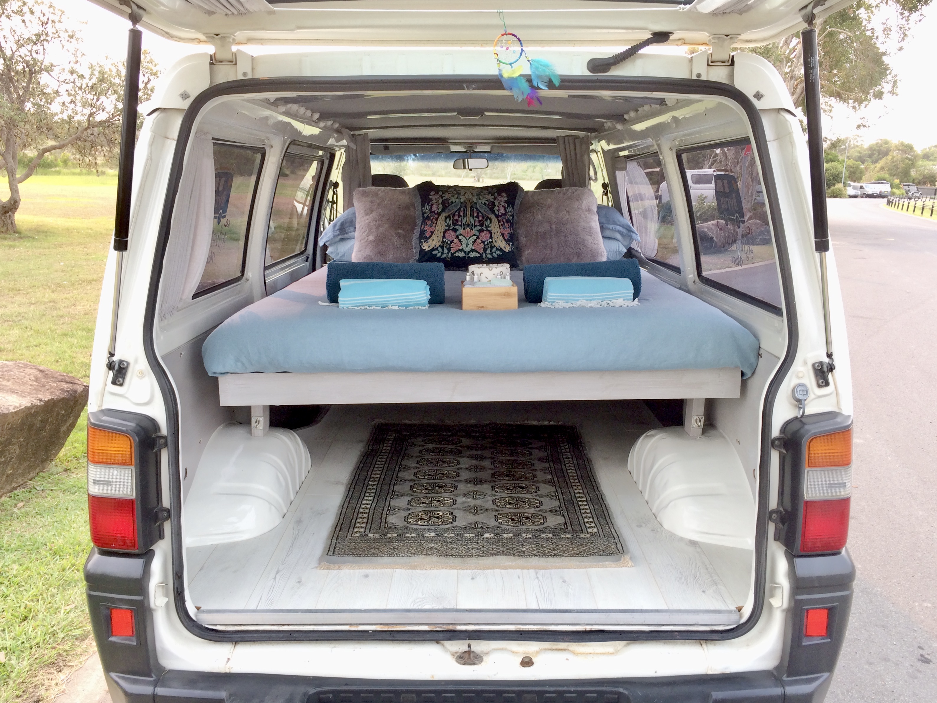 Explore in comfort! This cozy RV rental camper van interior features a bed, ready for your next travel adventure.. Mitsubishi Express 2001