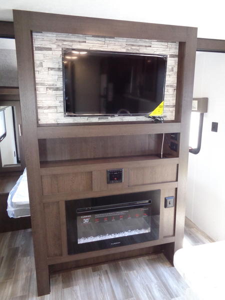 Explore this RV rental's cozy entertainment center: a large TV, built-in shelves, and an electric fireplace offer home-like comfort.. Forest River Salem Cruise Lite 2020