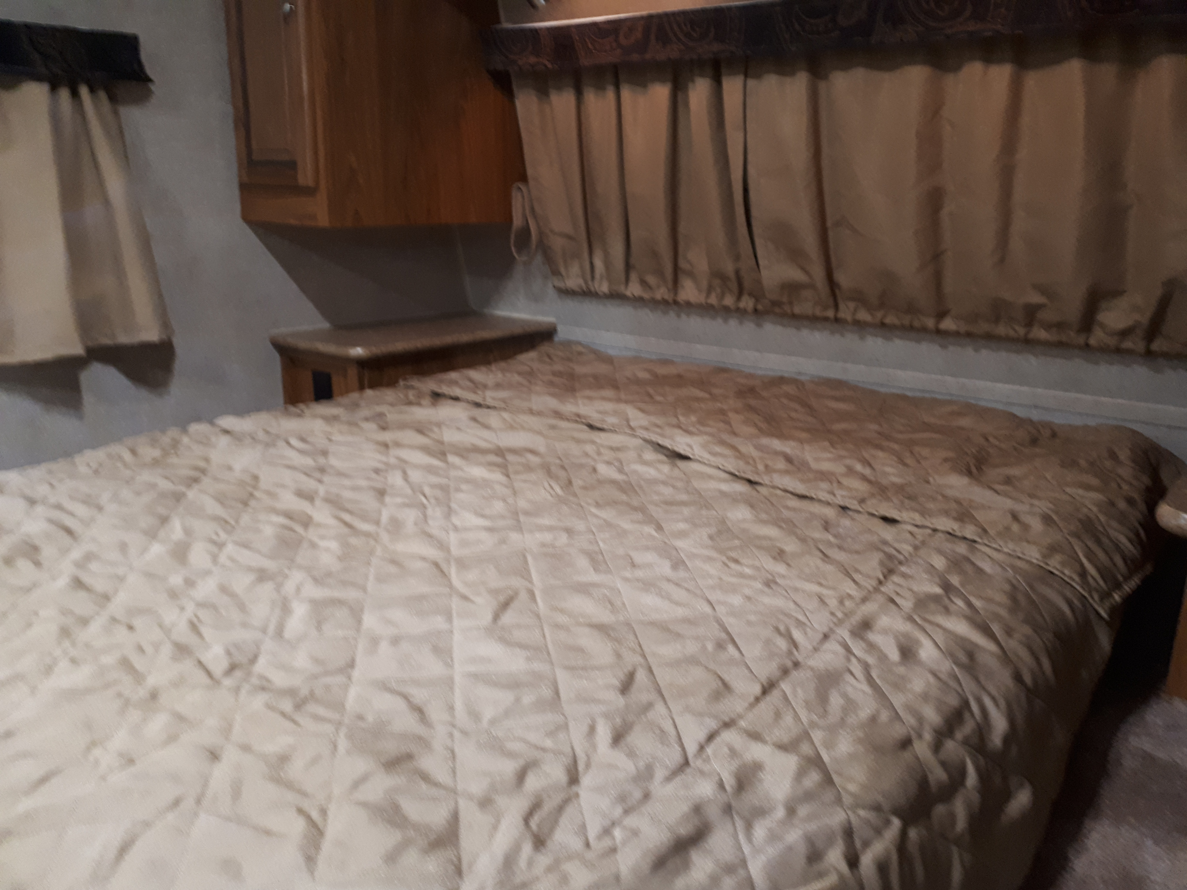 Visually impaired users: A cozy RV rental bedroom features a quilted comforter and patterned curtains.. Forest River Rockwood Mini Lite 2012