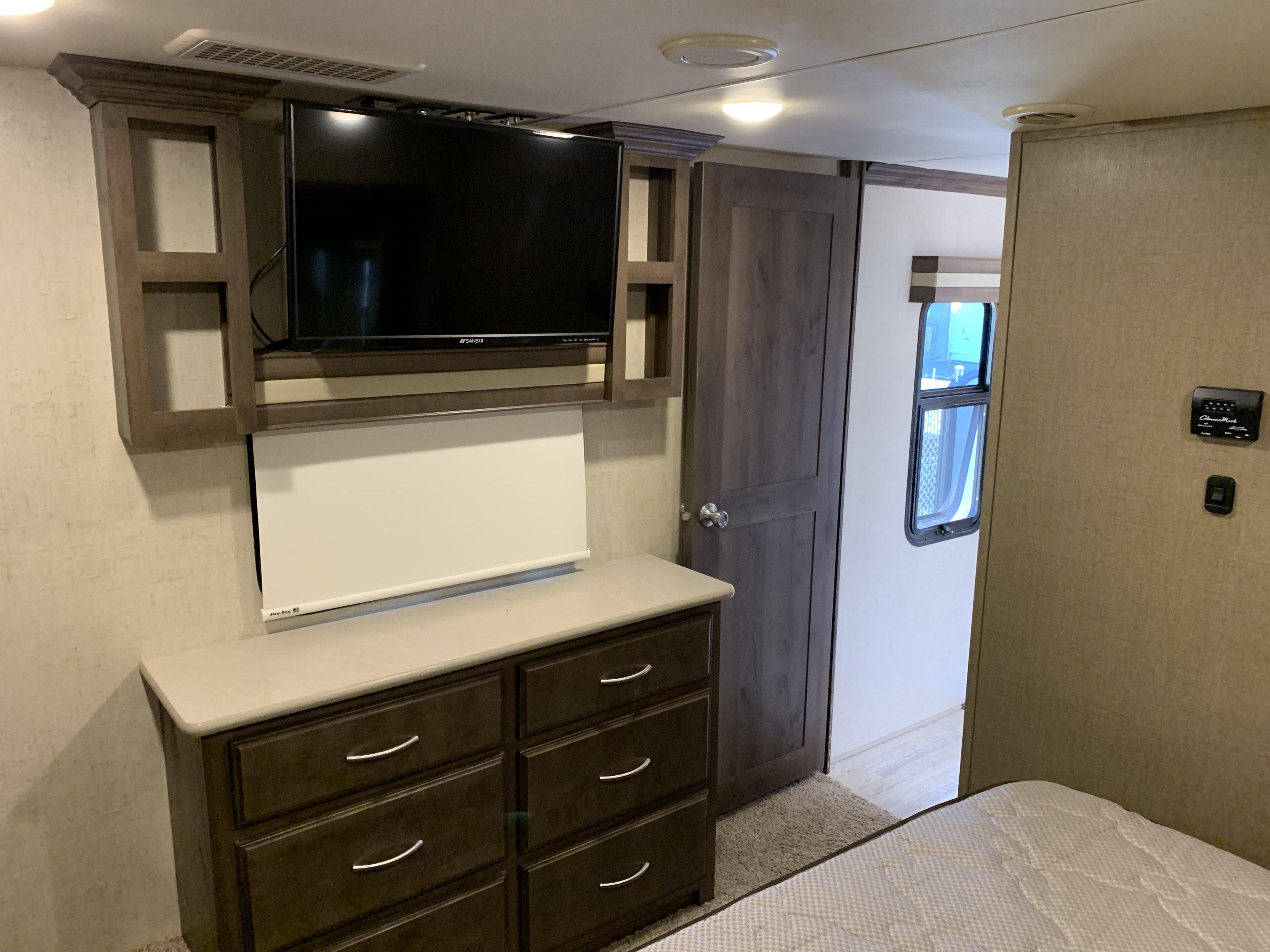 RV rental bedroom: mounted TV, dresser, storage, and door. Compact, functional interior.. K-Z Manufacturing Venom 2017