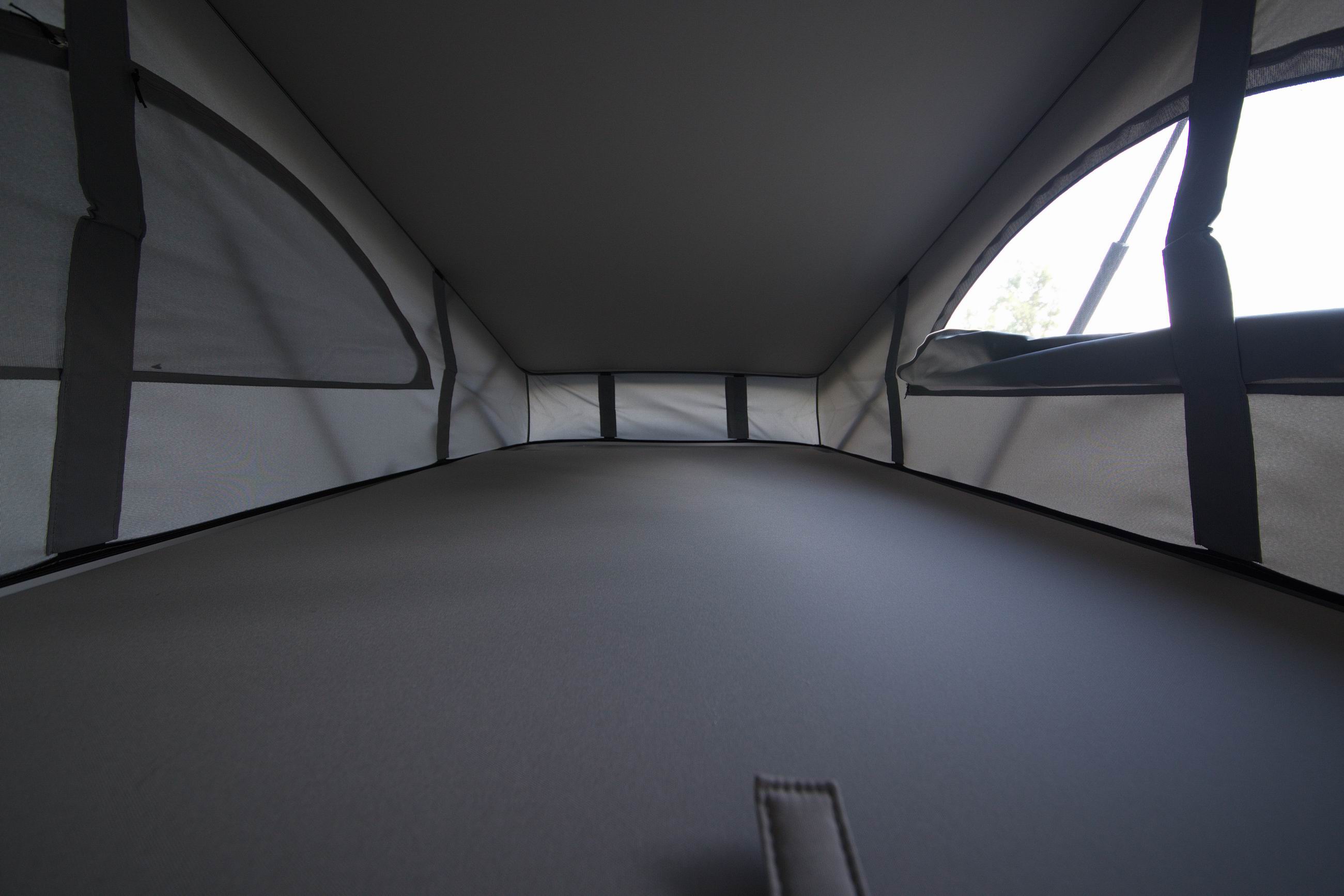 Inside a modern RV rental, this pop-up tent reveals a cozy, spacious sleeping platform with large mesh windows.. Volkswagen California Beach T6 2021