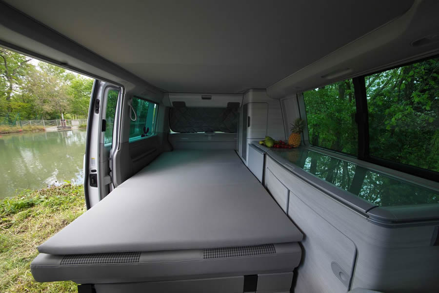 Spacious camper van RV rental interior: comfy bed, kitchen with fruit, scenic lake view. Ready for adventure!. Volkswagen California Coast T6 Boite Auto 2021