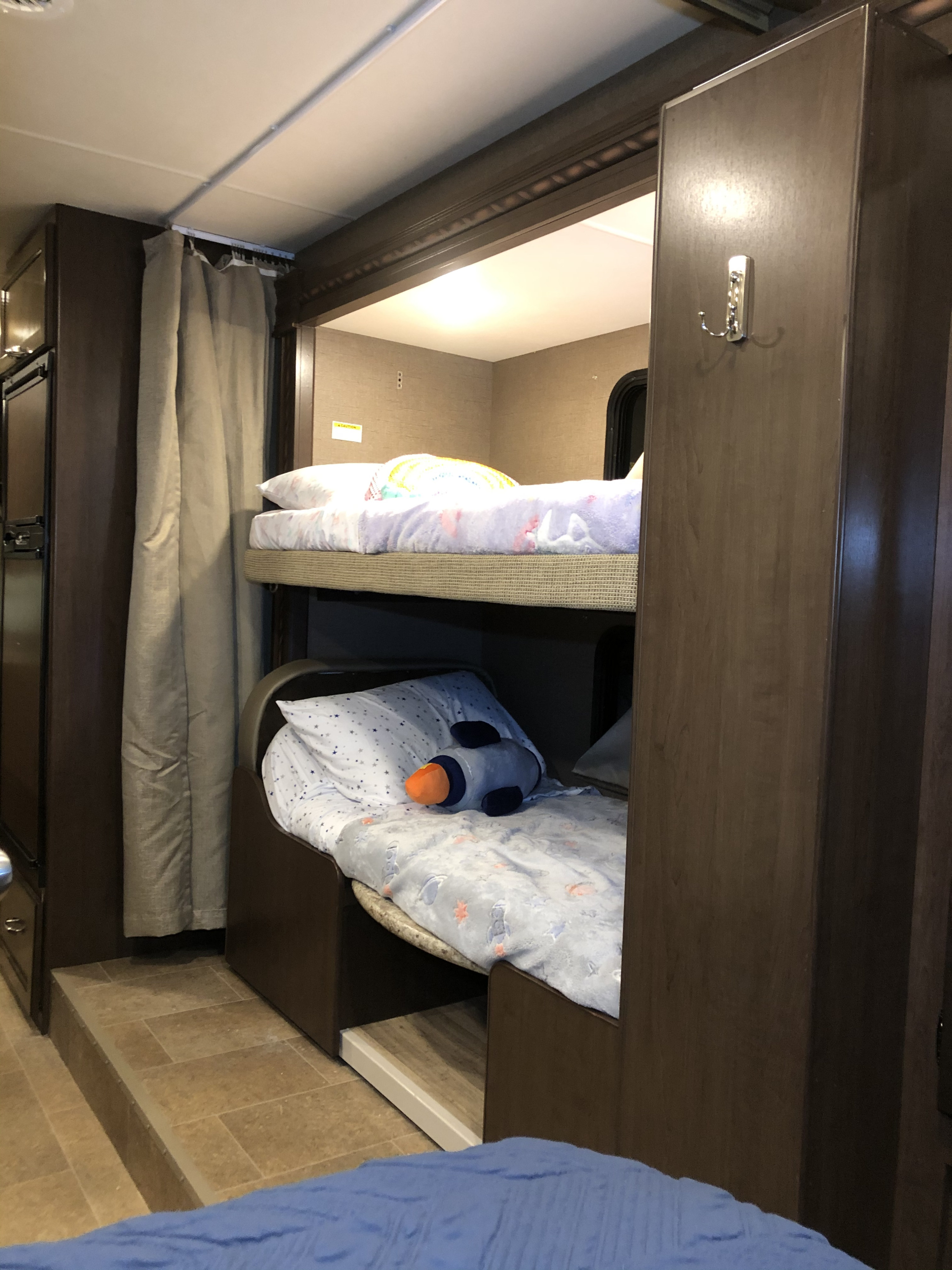 RV rental interior: Two cozy bunk beds with colorful bedding, one featuring a rocket toy. Compact and functional sleeping space.. Thor Motor Coach Freedom Elite 2017