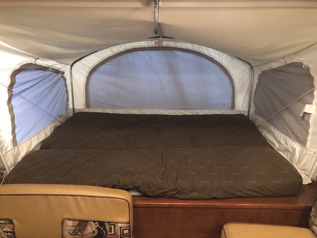 Comfortable pop-up camper bed, ideal for your RV rental. Features a wide, brown quilted mattress with arched windows.. Dutchmen Kodiak Express 172E 2014