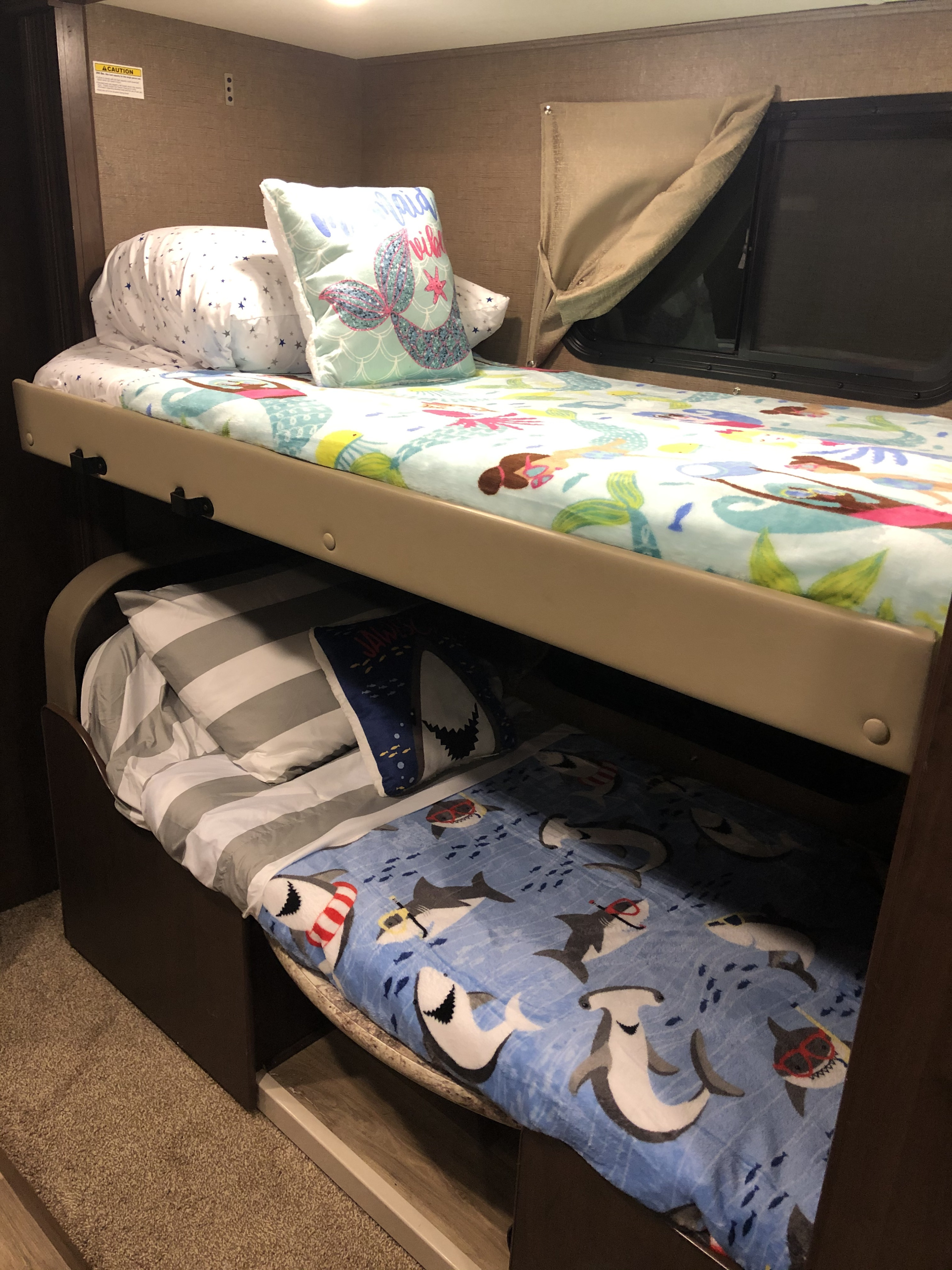 Cozy RV rental bunk beds, with one featuring a mermaid theme and the other sharks, offering a fun sleeping area for kids.. Thor Motor Coach Four Winds 2019