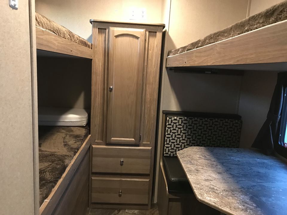 RV rental interior: cozy bunk beds, a central cabinet, and dinette seating. Compact and efficient living space.. Shasta Revere 2017