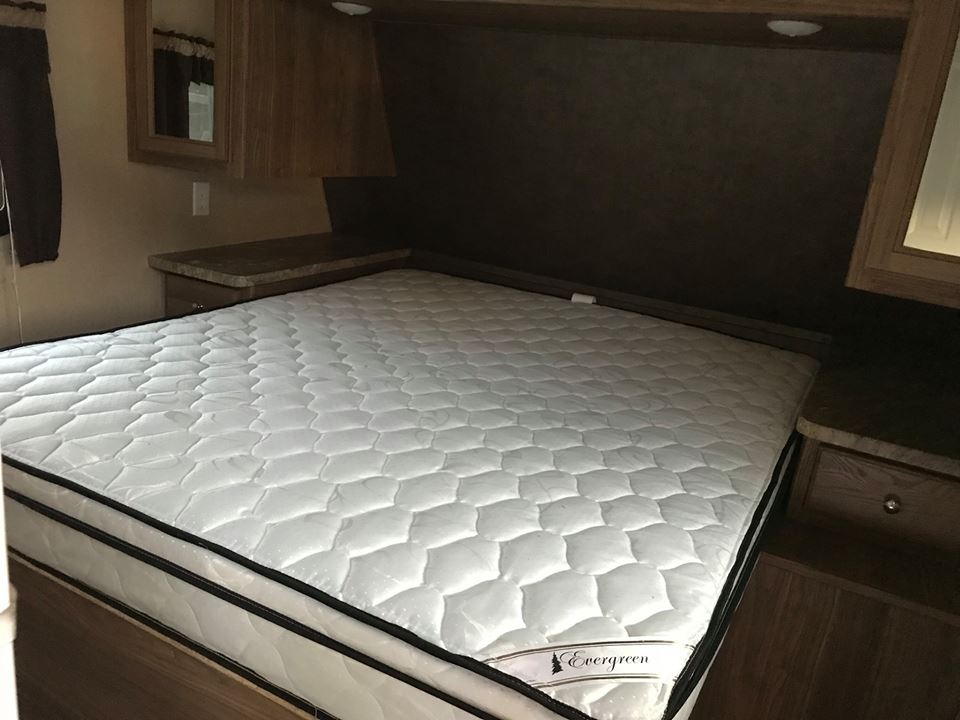 Clean RV rental bedroom with a comfortable Evergreen mattress, built-in storage, and mirror.. Shasta Revere 2017