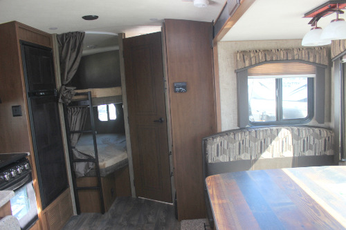 This RV rental interior features a dinette, refrigerator, and private bunk beds, ideal for families.. Outdoors RV Timber Ridge Titanium 2019