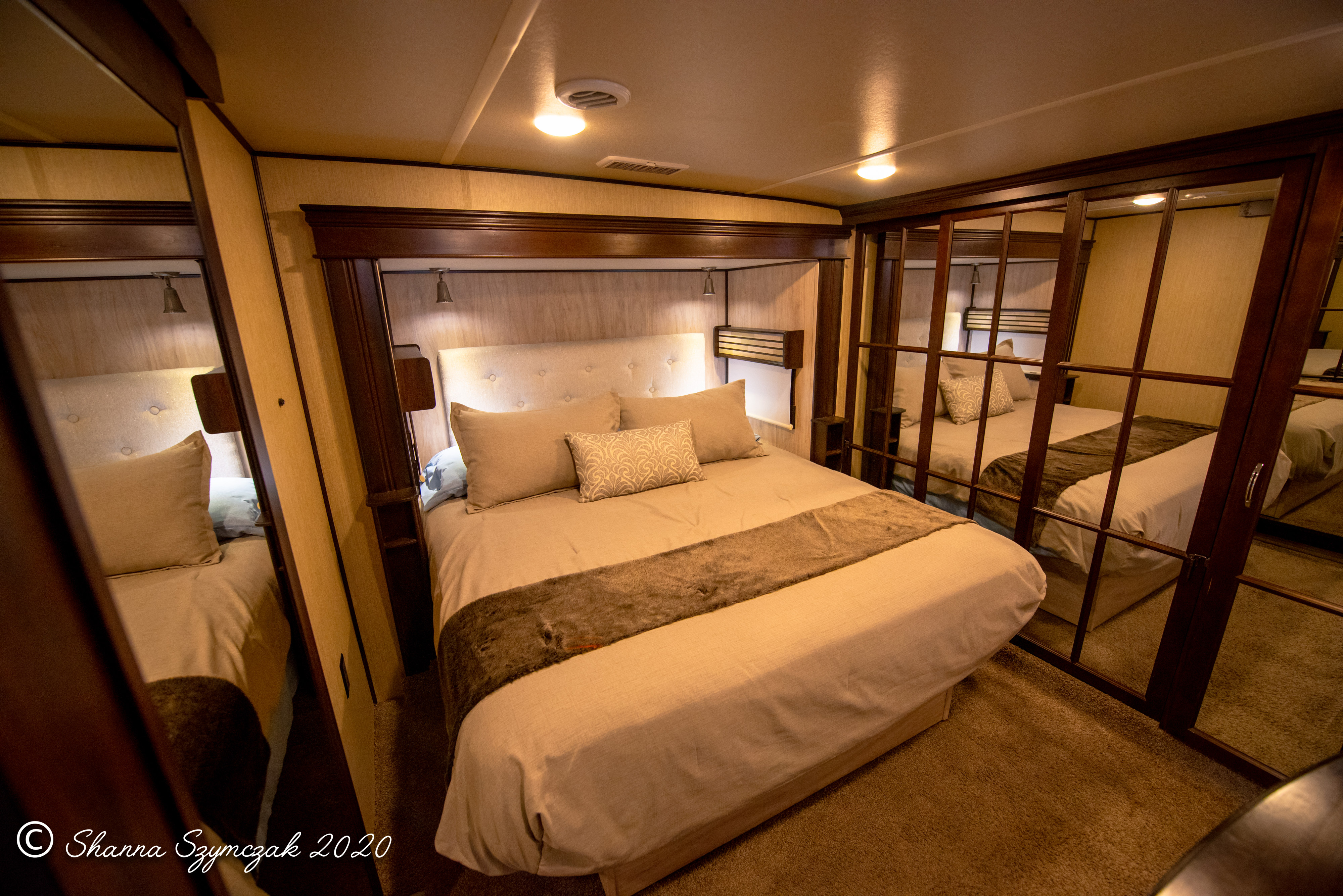 Comfortable RV rental bedroom featuring a queen bed with plush bedding, built-in storage, and a mirrored wardrobe.. Palomino Columbus 2017