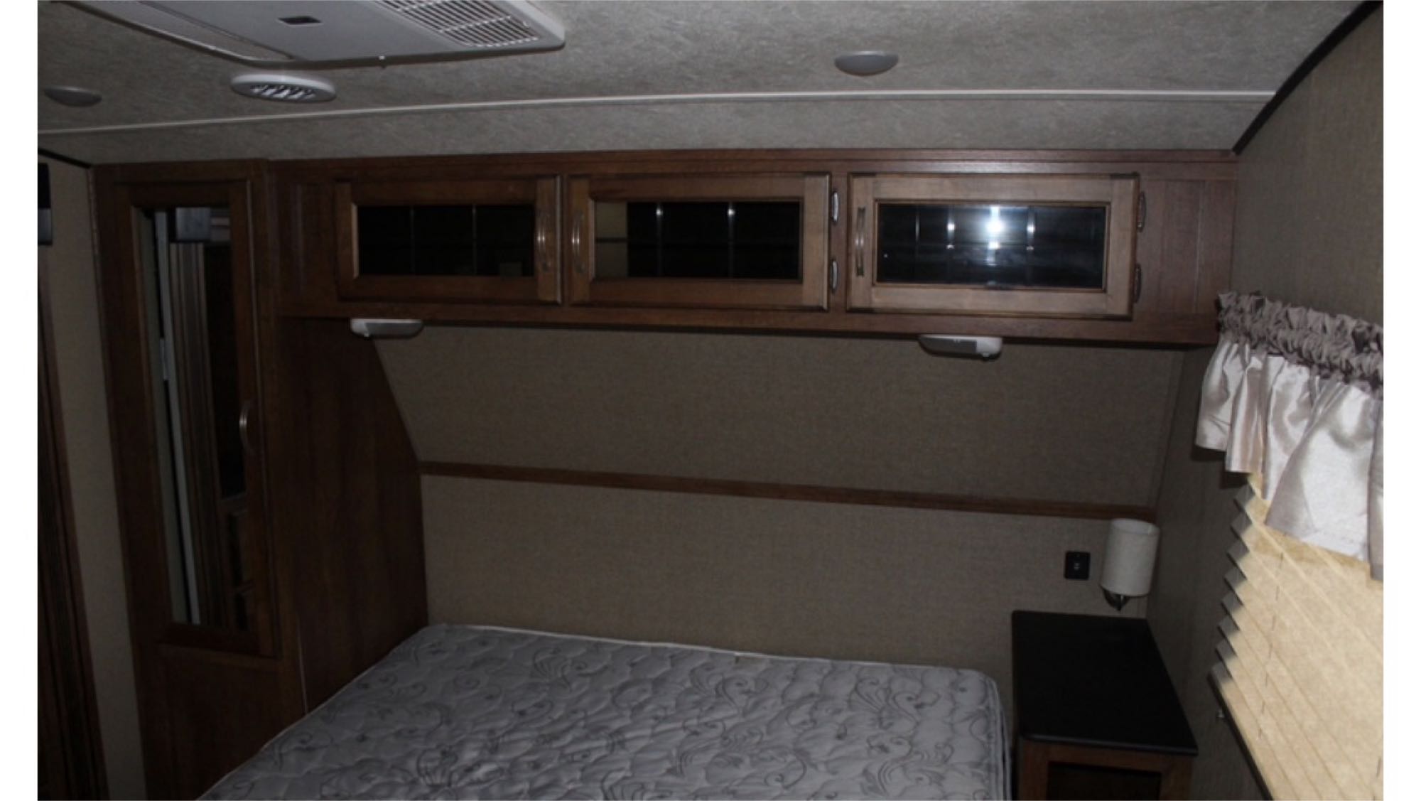 Comfortable RV rental bedroom interior with a bed, overhead cabinets, wardrobe, and nightstand.. Coachman Chaparral 2017